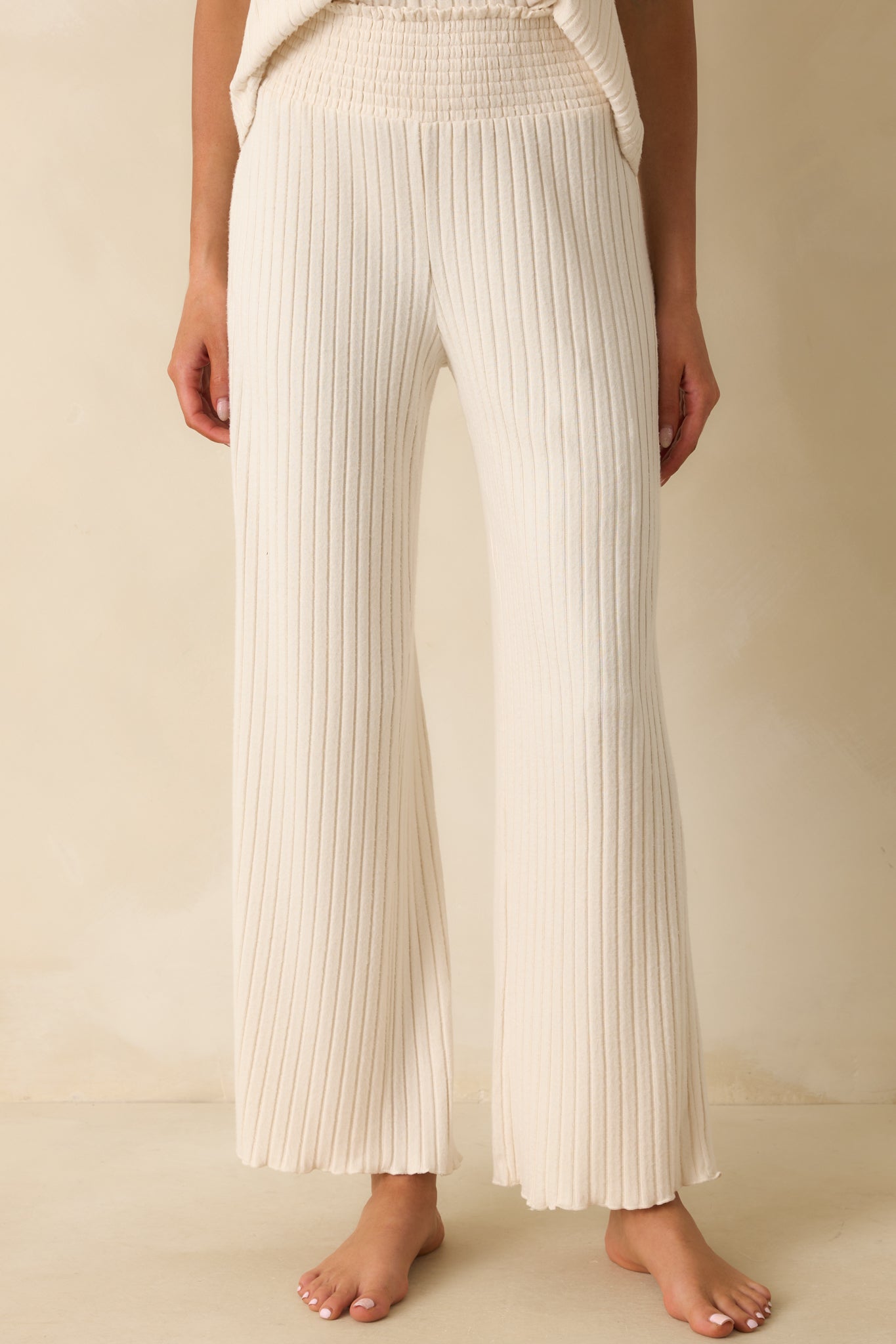 Close view of the smocked high-rise waistband on the ivory ribbed pants.