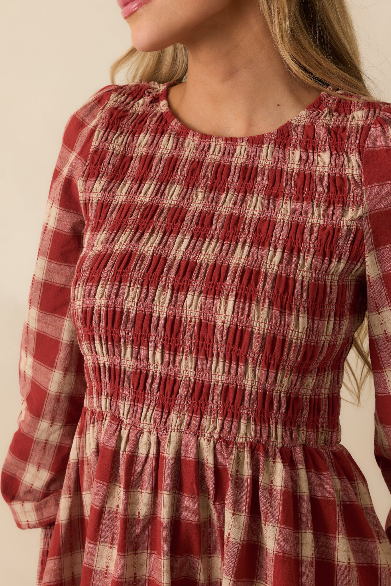 Close-up of the brick red gingham fabric with smocked stitching and textured finish.