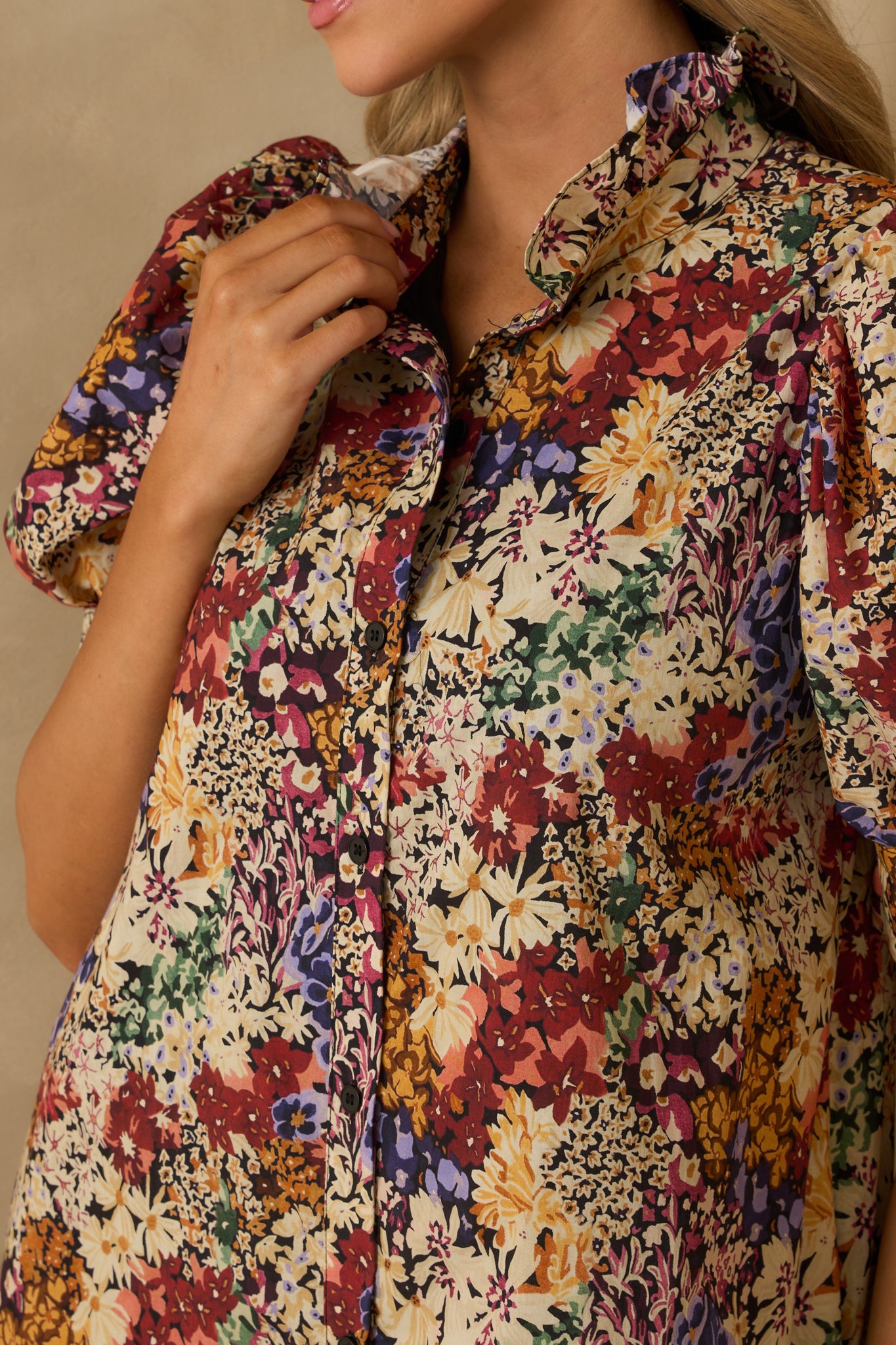 Close-up of the ivory floral maxi dress showing the ruffle trim neckline, button front, and black top stitching.
