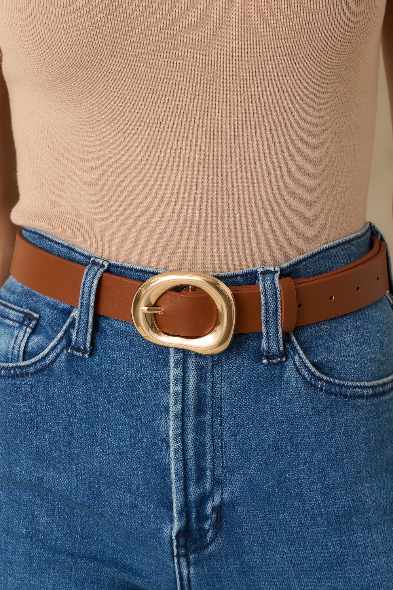 Zoomed-in image focusing on the texture of the faux leather and the open, irregular shape of the polished gold buckle.