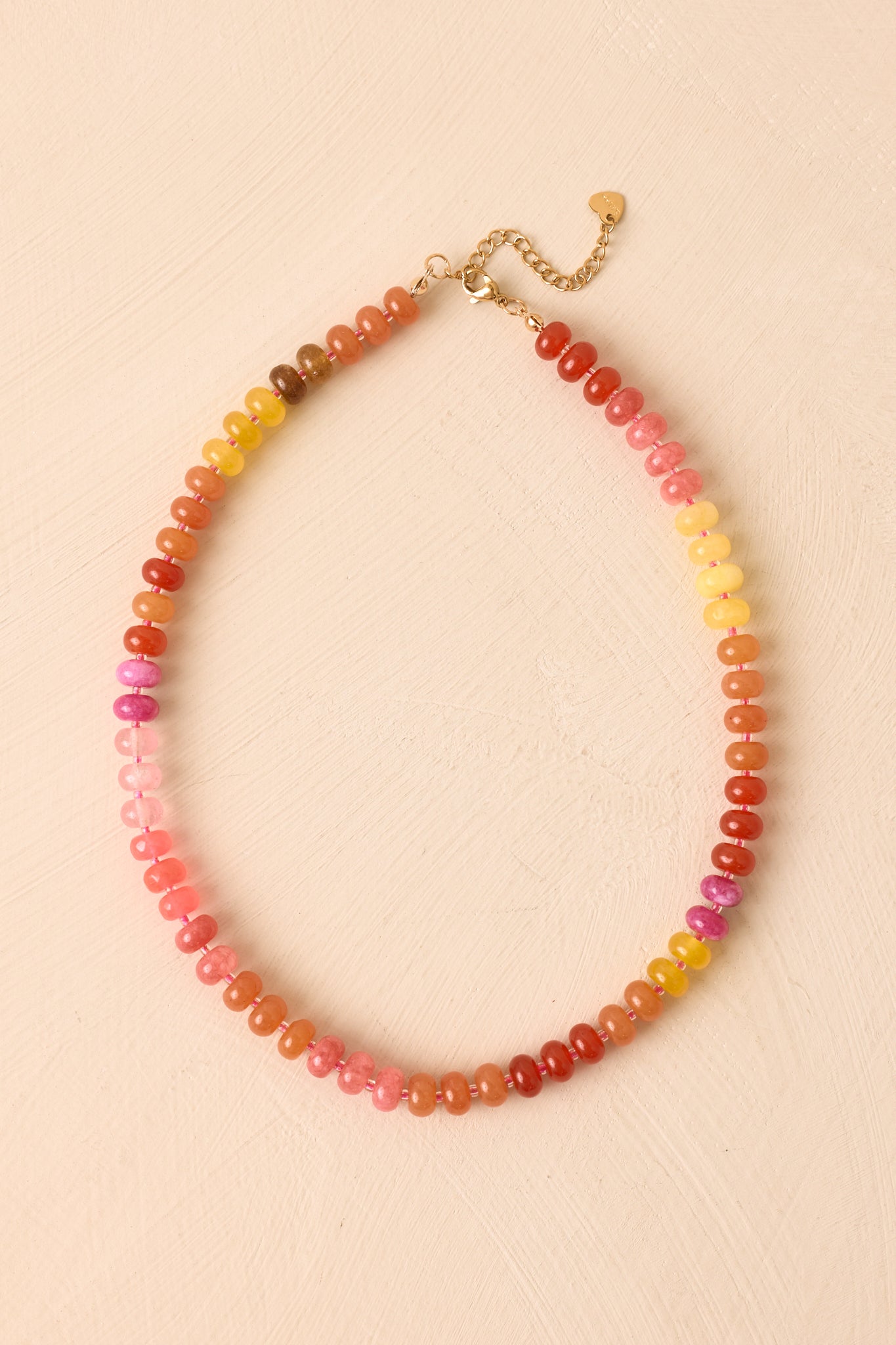 Multicolor beaded necklace displayed against a beige background, highlighting the cheerful glass beads and gold-tone accents.