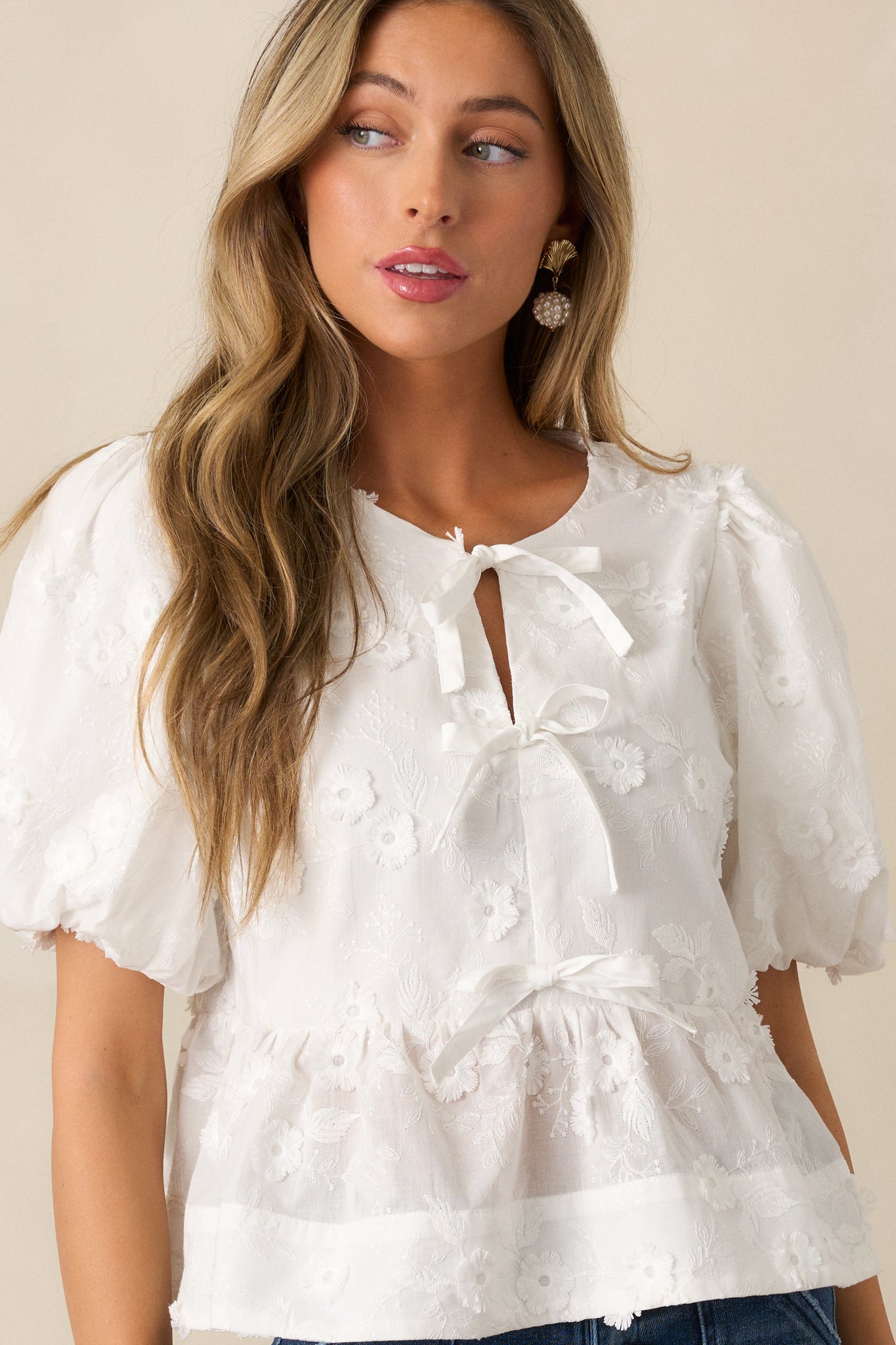 Close-up cropped photo highlighting the puff sleeves and bow accent at the chest of the blouse.