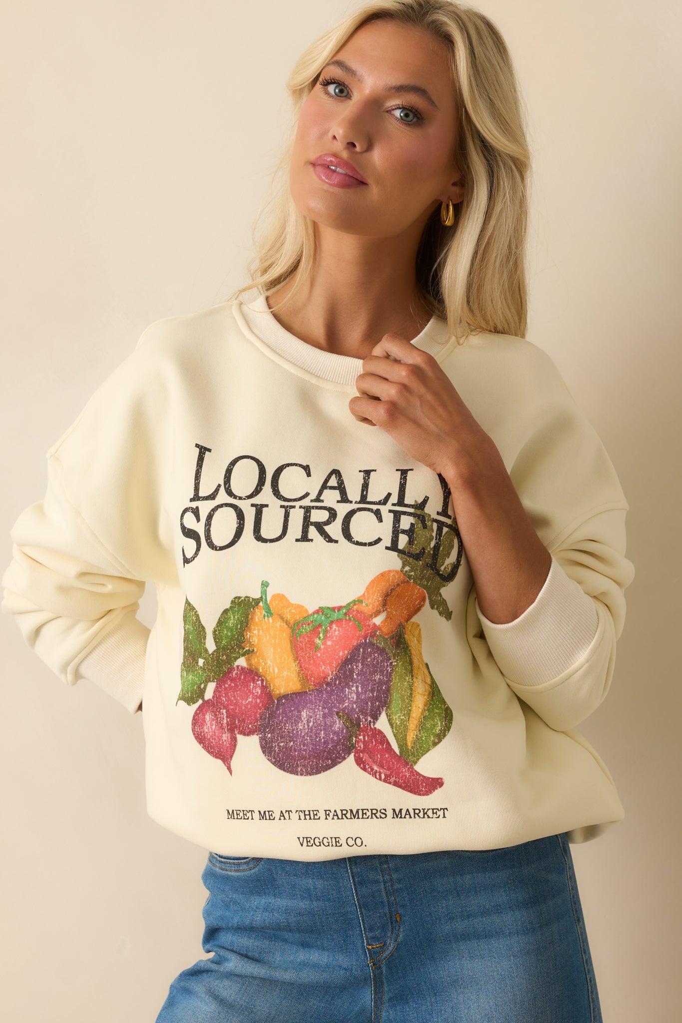 Cropped front shot of ivory sweatshirt highlighting colorful farmer’s market vegetable artwork.