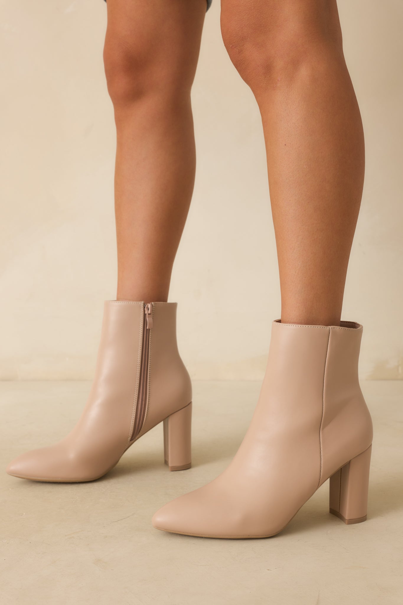 Beige ankle boots with pointed toes and a block heel, highlighted with an outer seam detail.