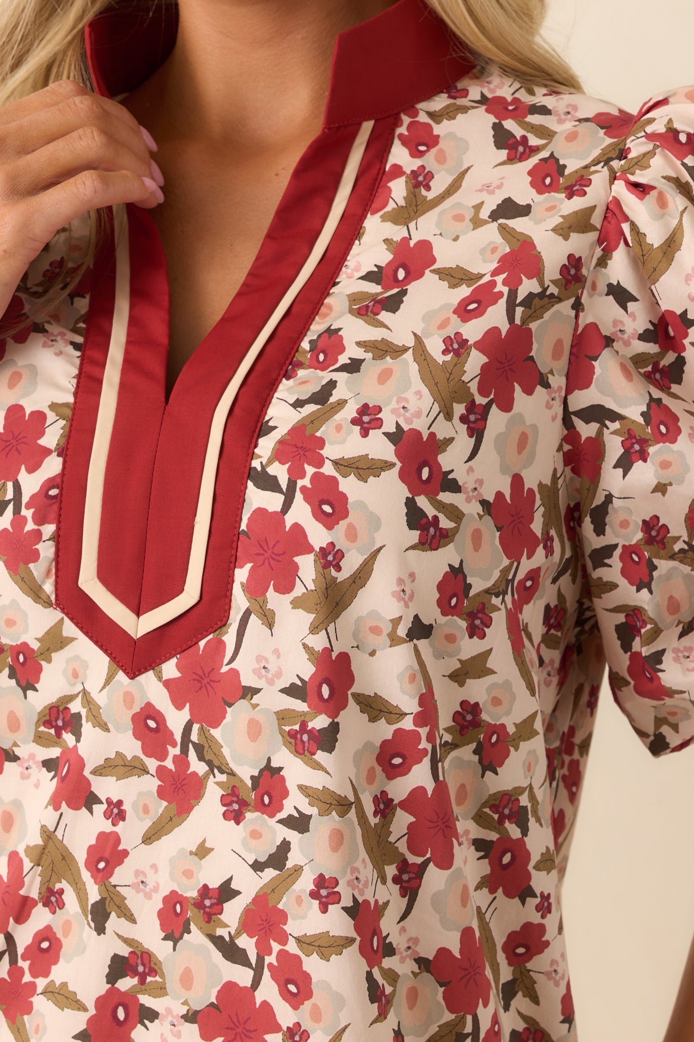 A detailed close-up capturing the beige trim along the neckline and puff sleeve, with emphasis on the floral fabric texture.