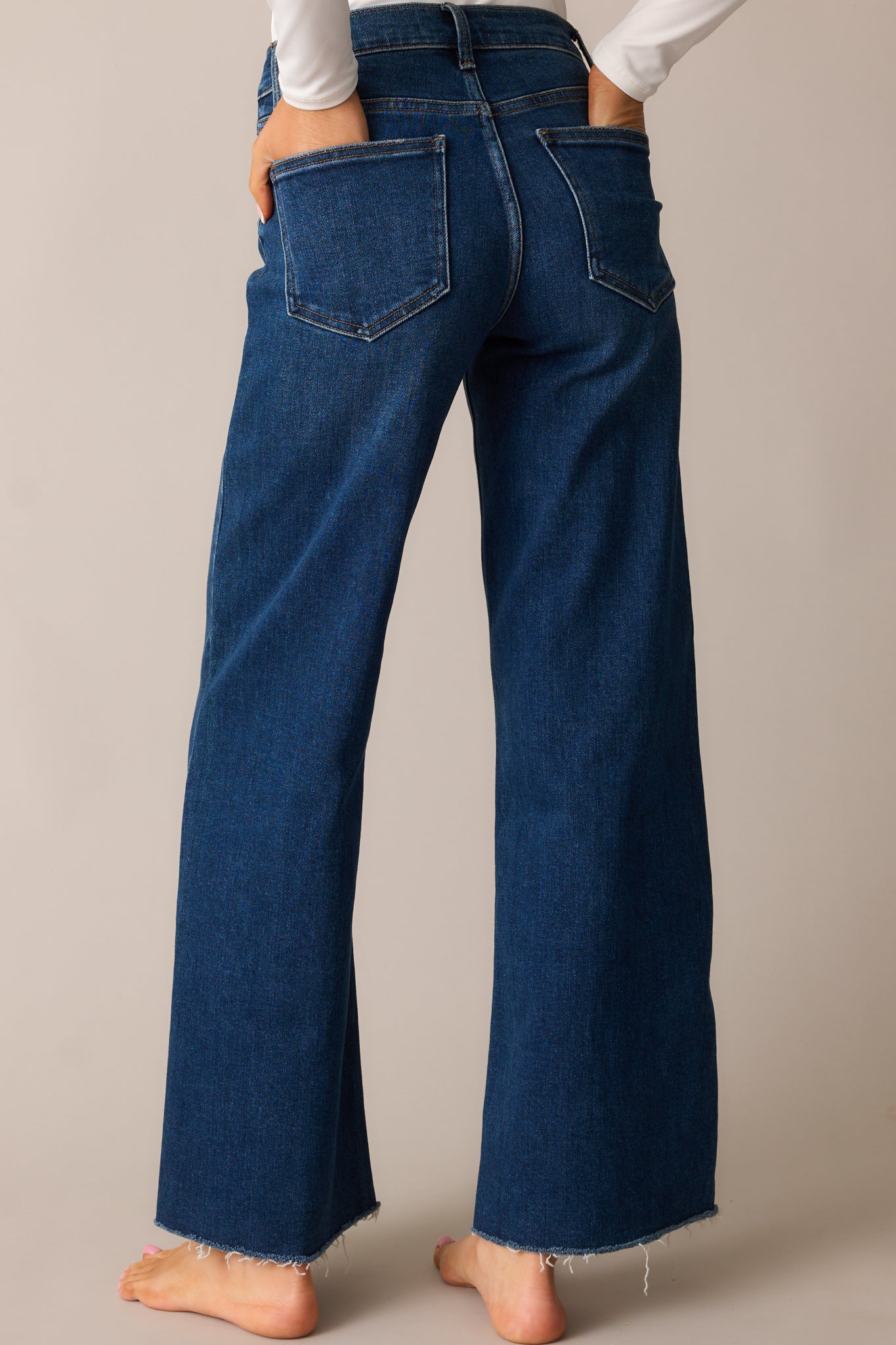 Dark wash high-waisted jeans shown from behind, emphasizing the fit, back pockets, and wide straight-leg cut.