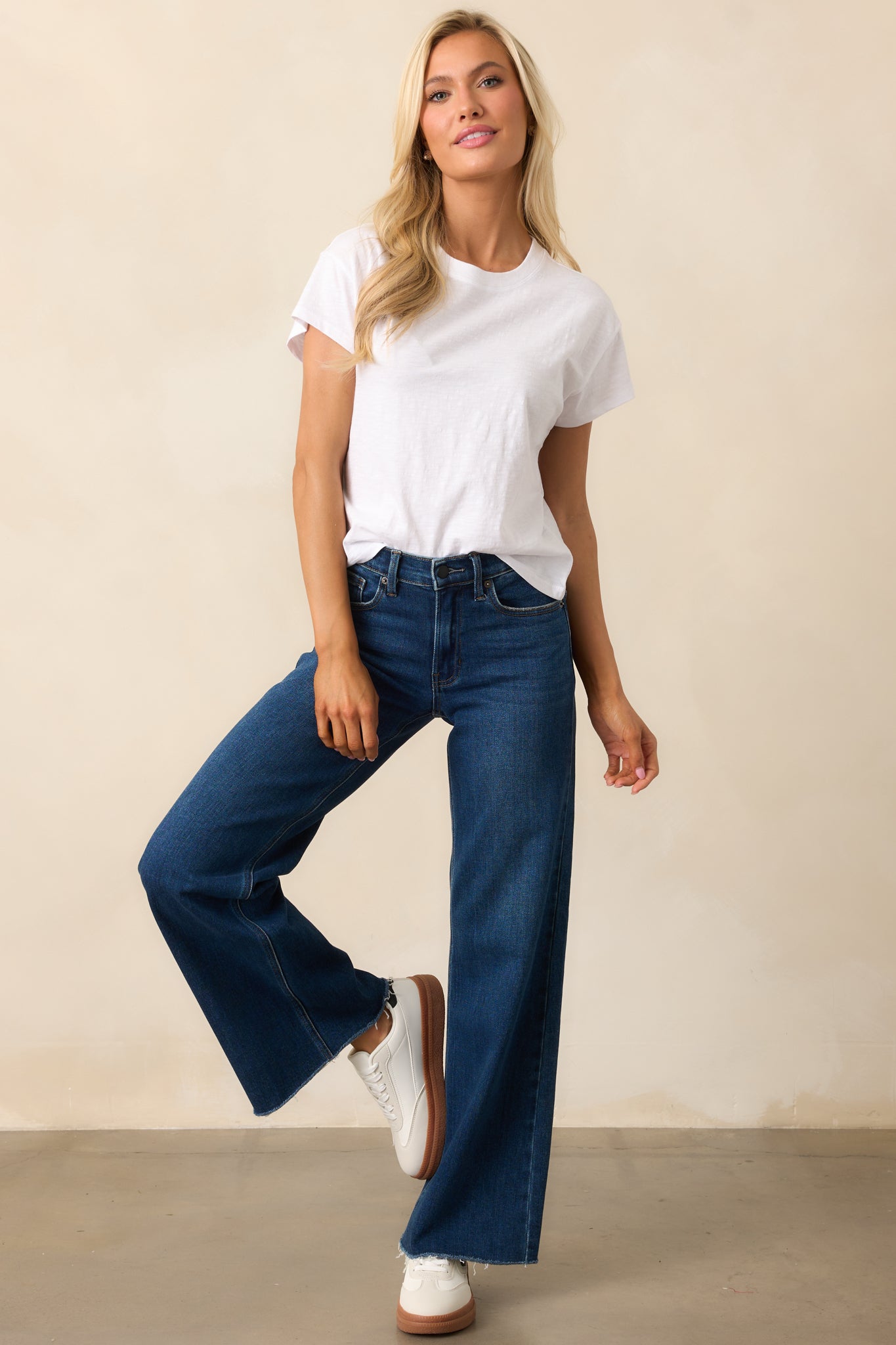 Dark wash jeans with a high-waisted fit, wide straight legs, and a raw bottom hem for a laid-back touch.