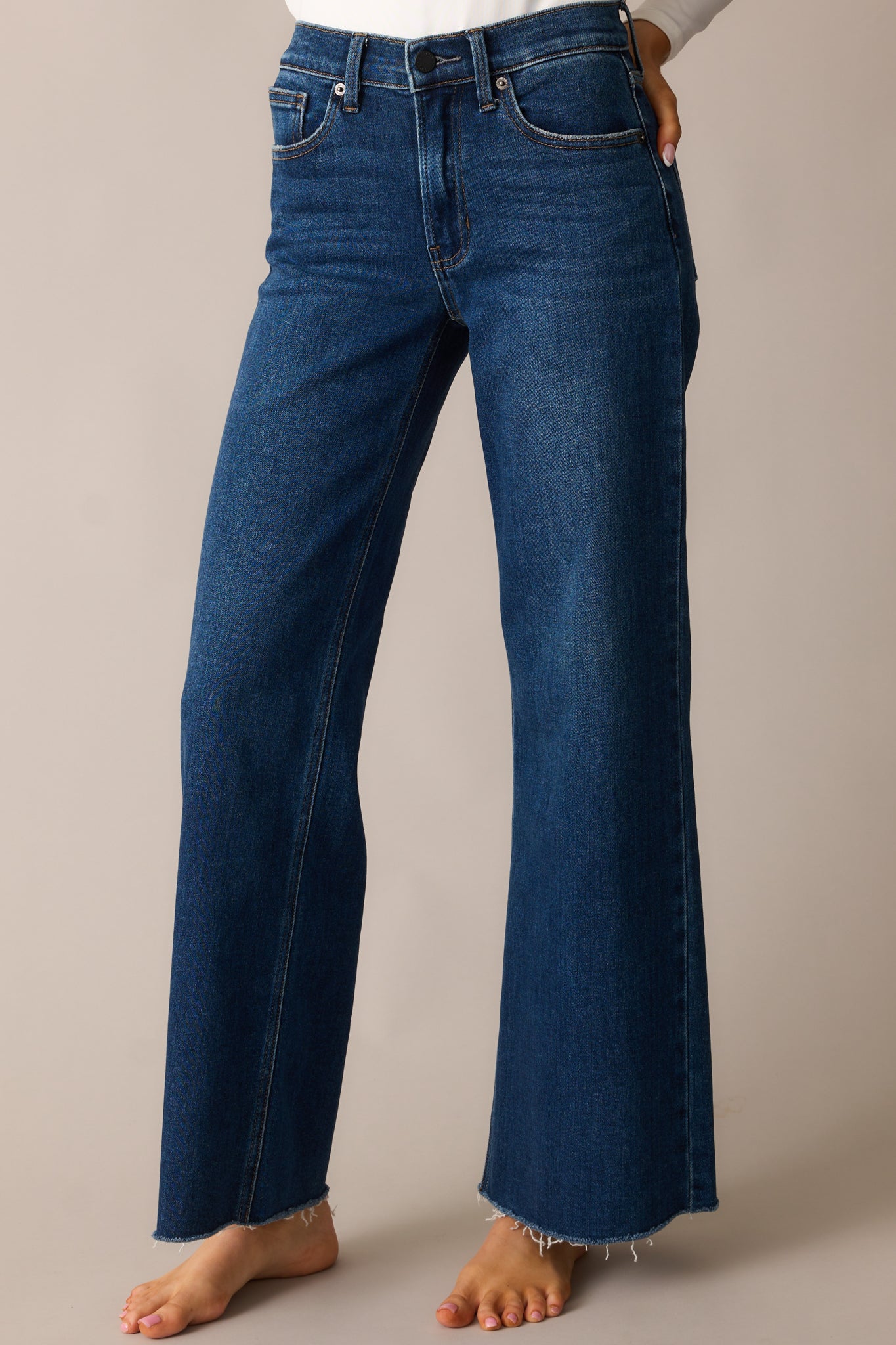 A detailed view of the wide straight-leg jeans, highlighting the raw bottom hem and relaxed fit.