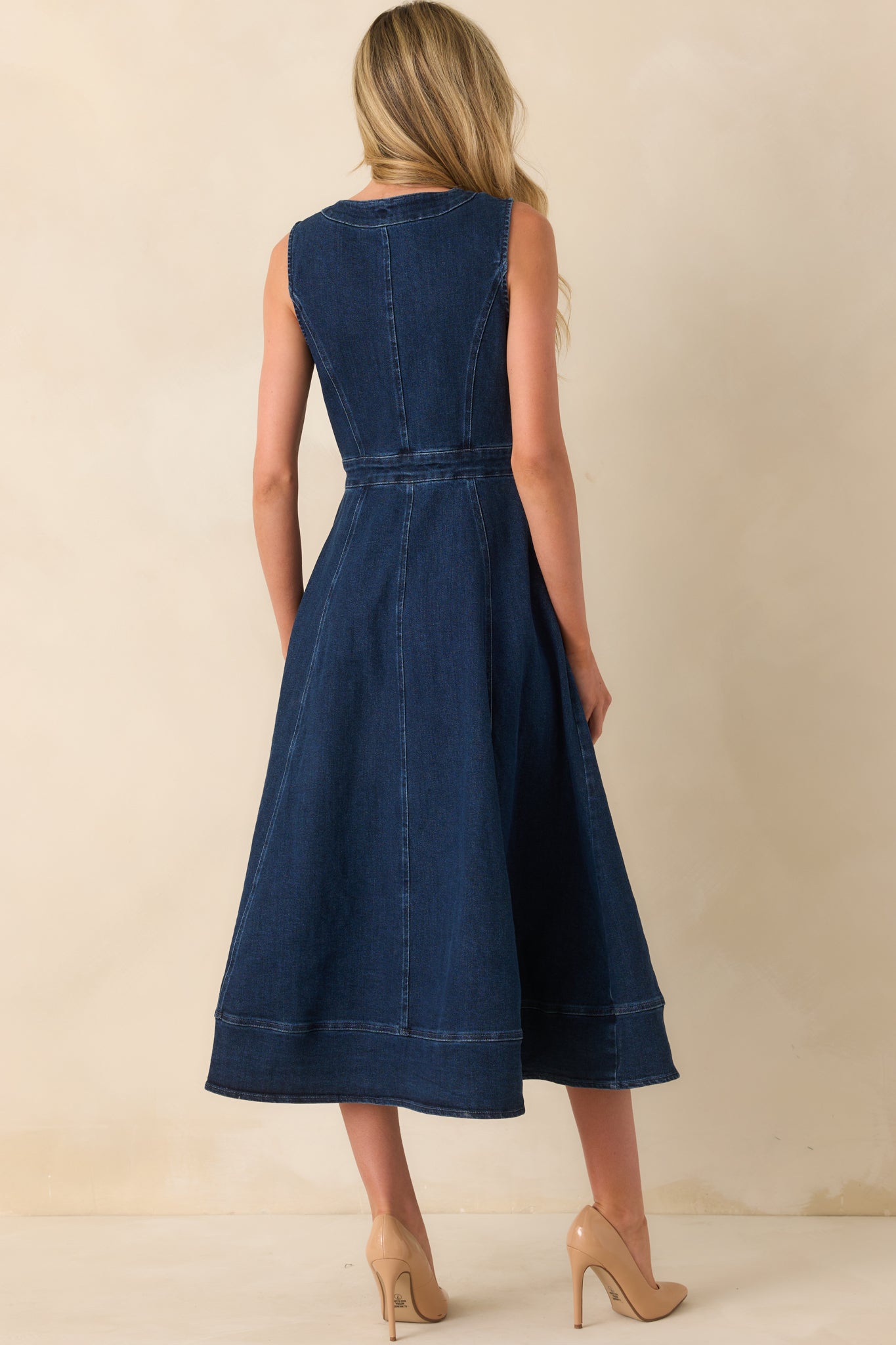Back view of dark wash midi dress with paneled design, fitted waist, and smooth sleeveless cut.