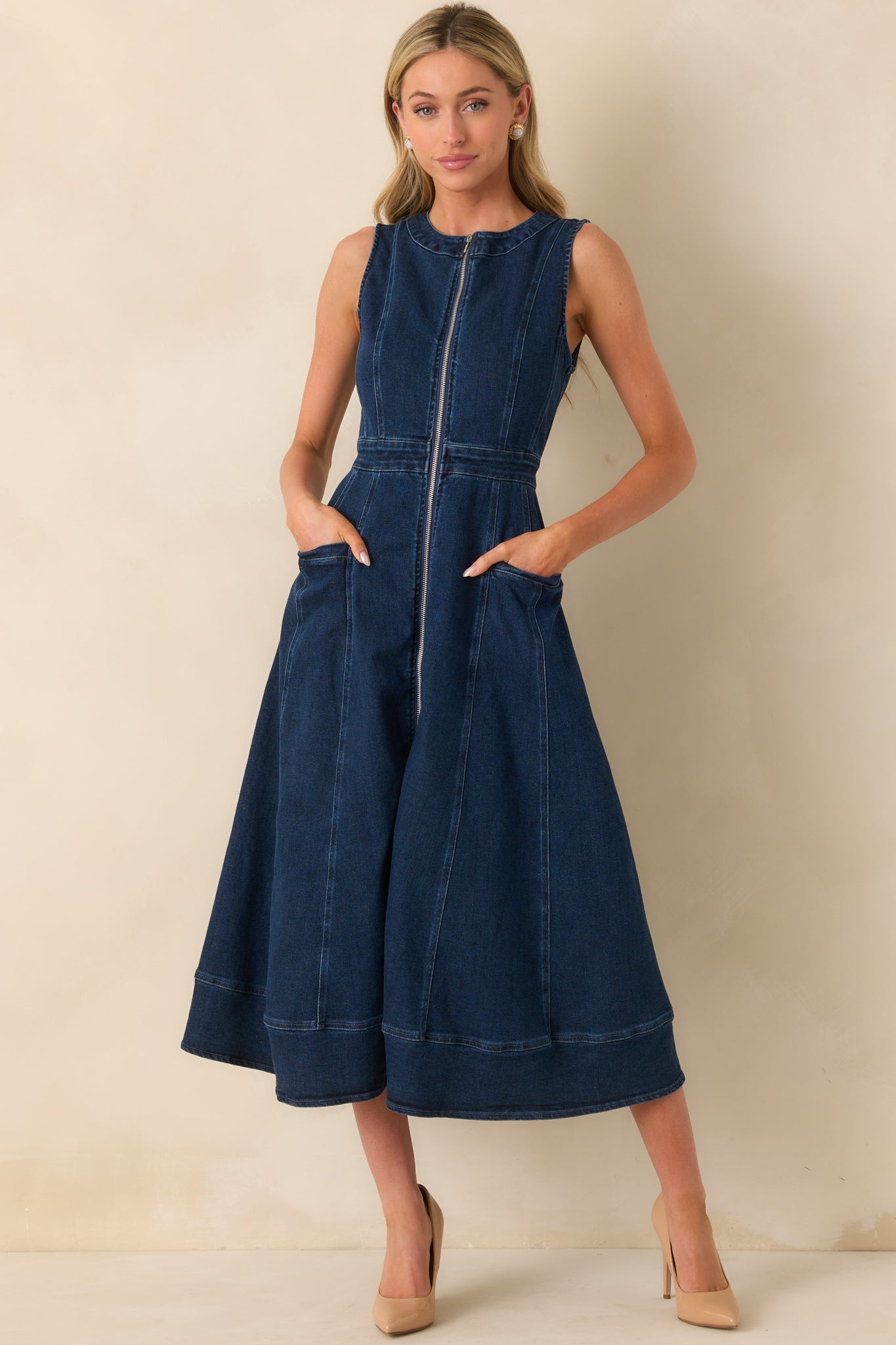 Dark wash midi dress featuring a sleeveless design, paneled construction, and functional pockets, front facing.