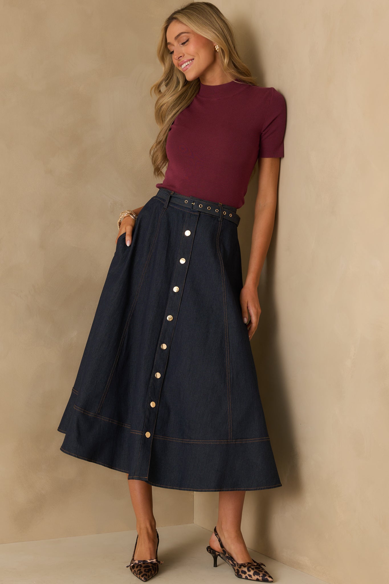 Front-facing full view of the dark wash skirt, showcasing its structured silhouette, button front, and subtle seam detailing.