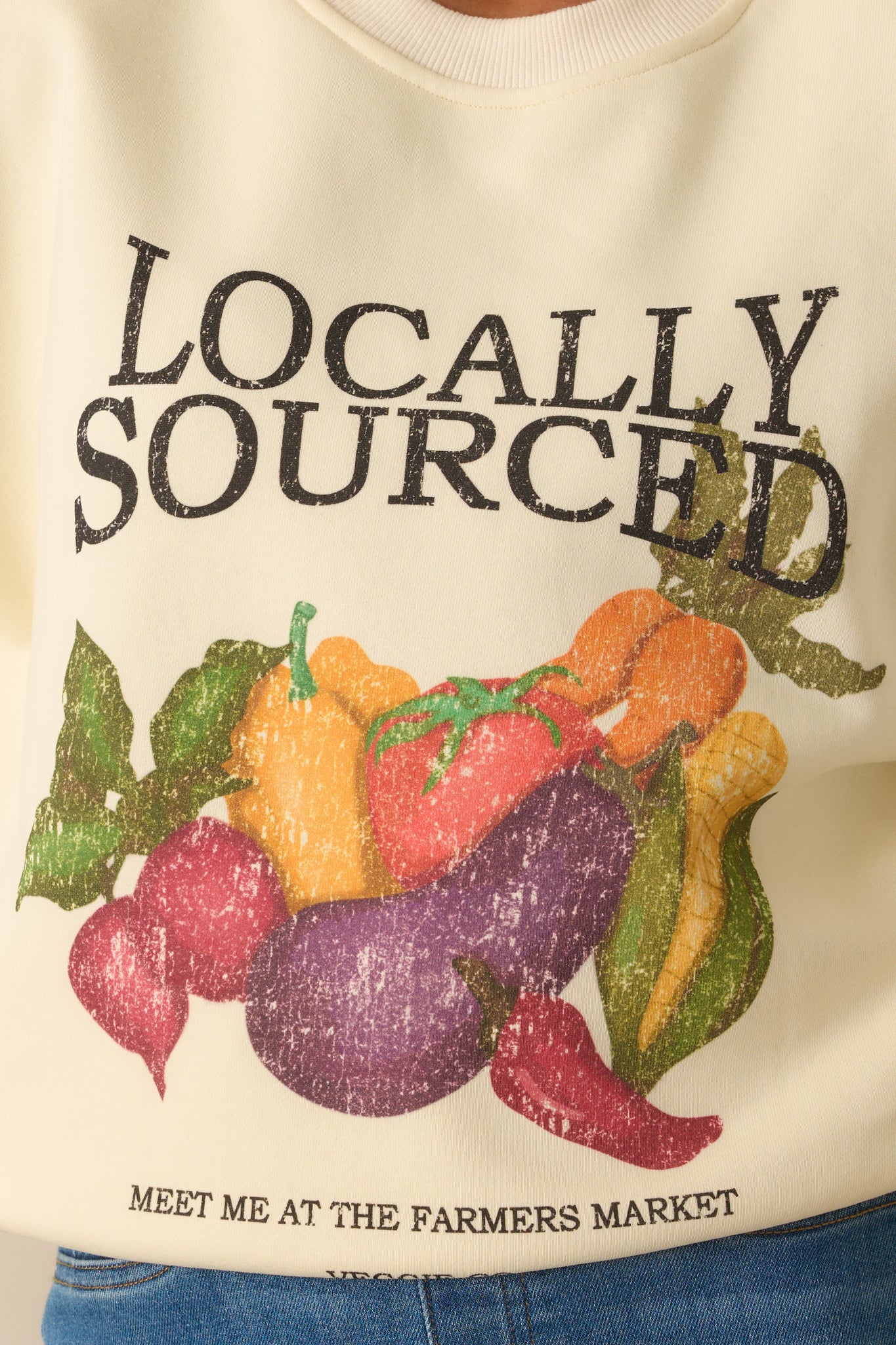Detailed close-up of ivory sweatshirt’s textured cotton fabric and vegetable market graphic.