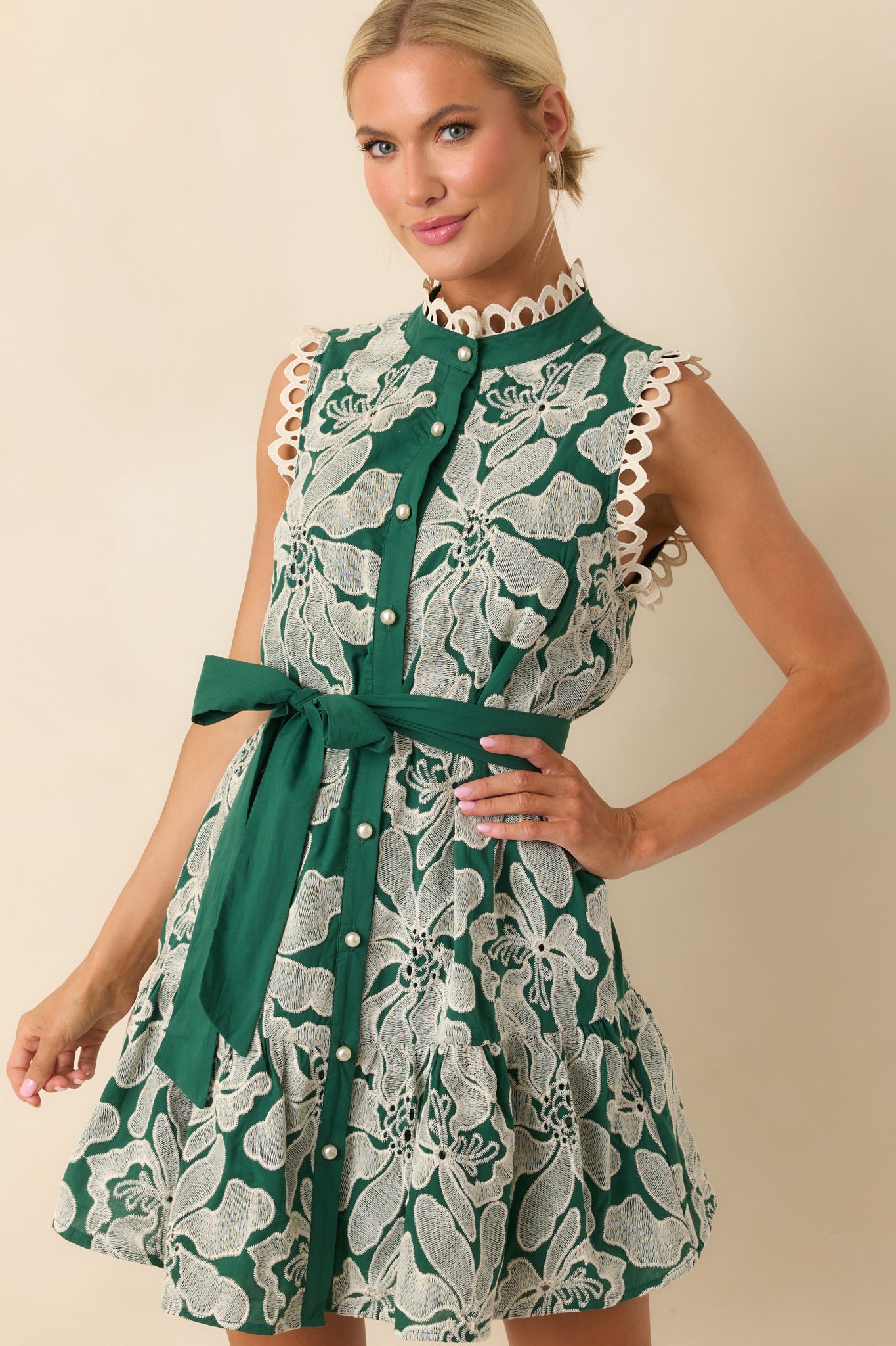 A cropped view showing the white floral embroidery and texture of the green fabric.