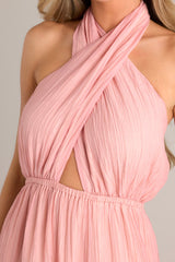 Close up view of the neckline of this Pink dress featuring a self-tie halter neckline with a back tie closure, an alluring open back, an elastic band at the back of the bust for a comfortable fit, an elastic waistband, and a flowing skirt.
