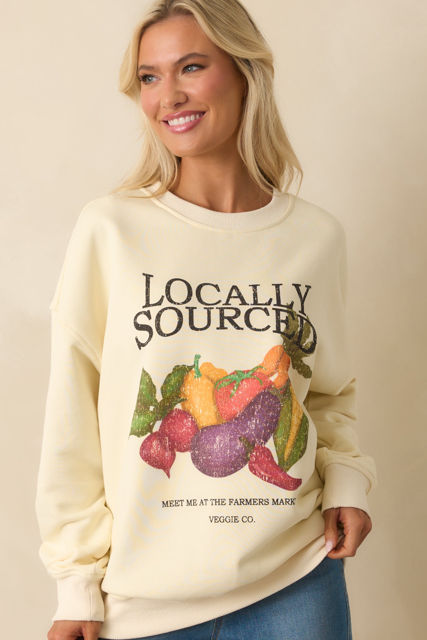 Focused cropped image of ivory cotton sweatshirt showing relaxed shoulders and market print.