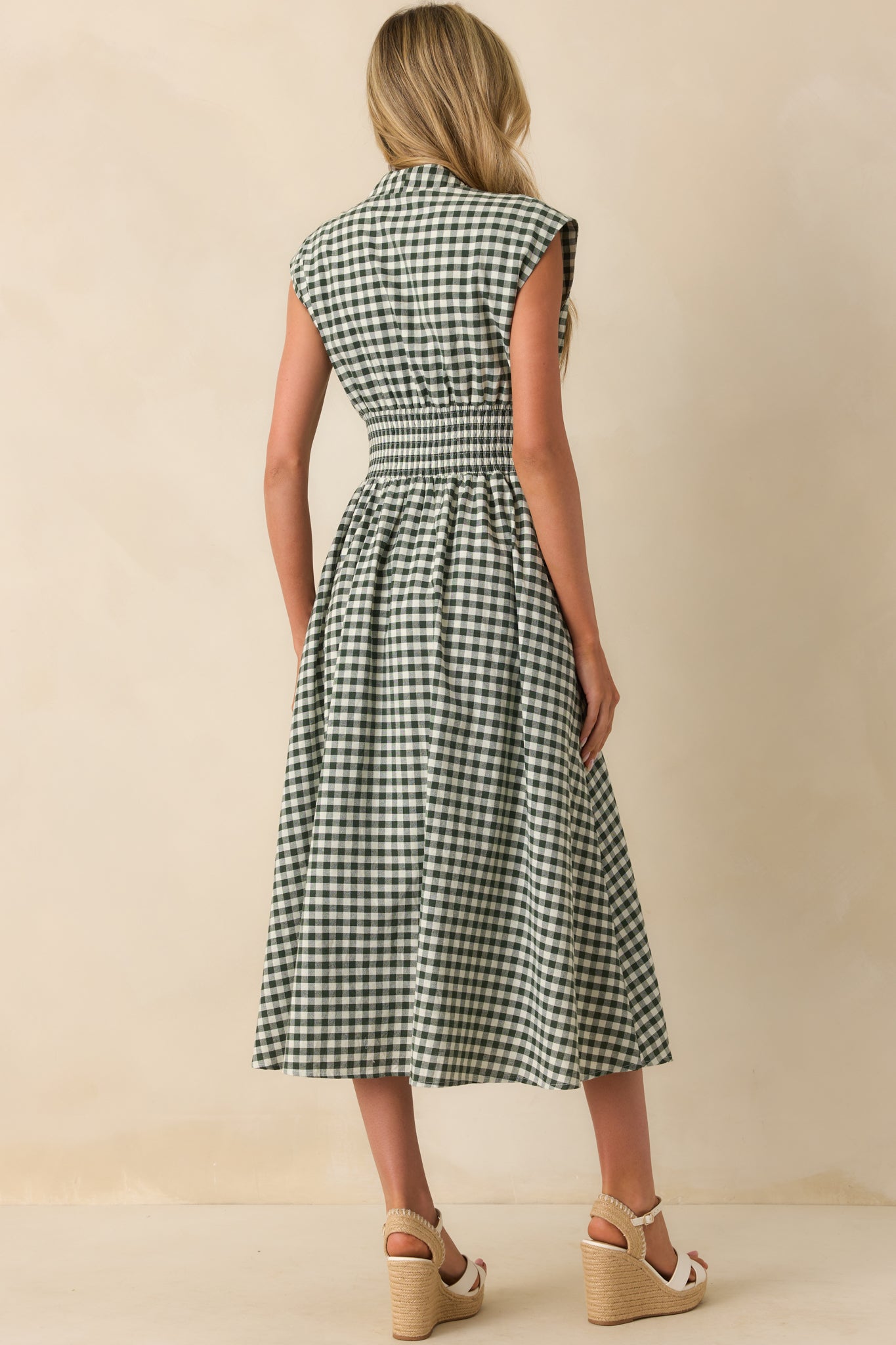 A view from behind showing the green gingham midi dress with capped sleeves and fitted smocked waist.