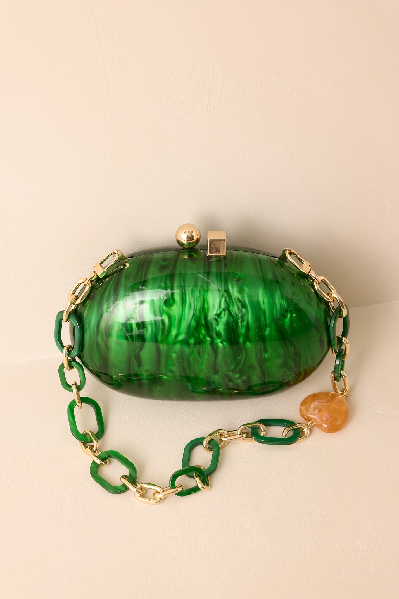 Glossy emerald clutch accented with a detachable resin-and-gold chain strap featuring a bold amber bead.