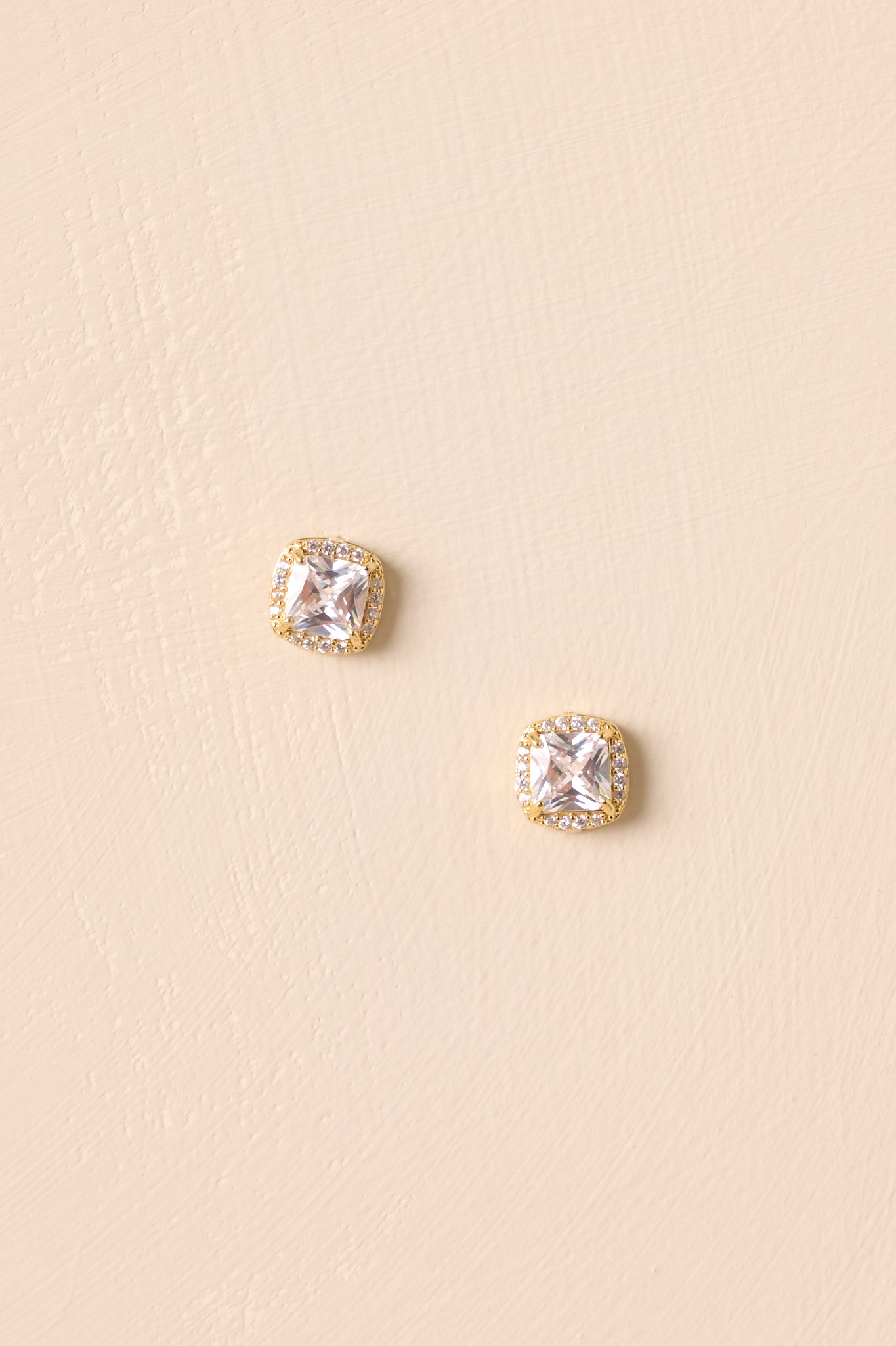 Pair of gold-dipped stud earrings with cushion-cut cubic zirconia centers and pavé halos.