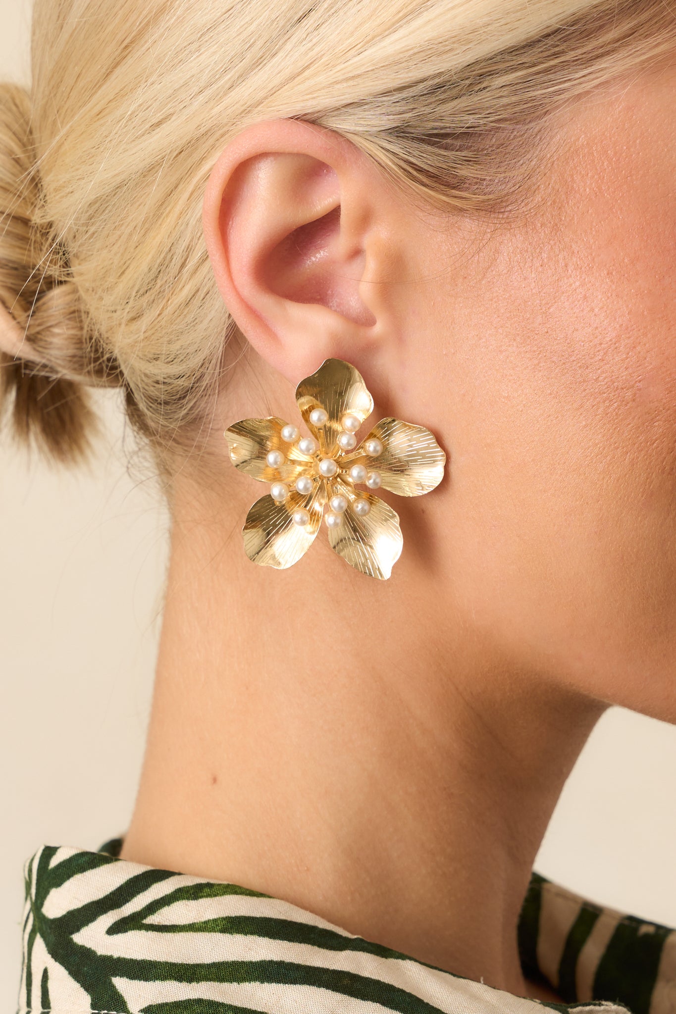 A zoomed-in shot of one earring, detailing the intricate texture of the gold petals and layered ivory pearl cluster.