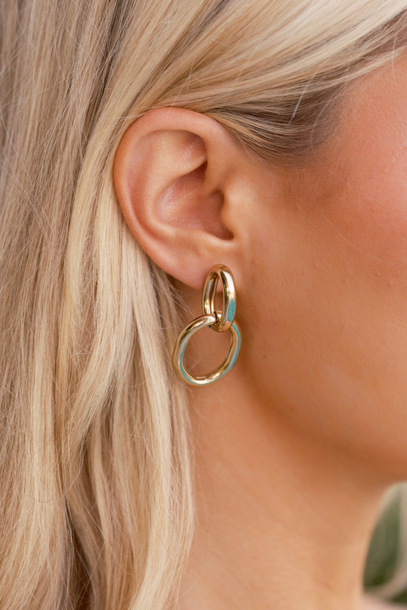 Front-facing view of the earrings showing the two interlocking gold circular links with a subtle shine and smooth finish.