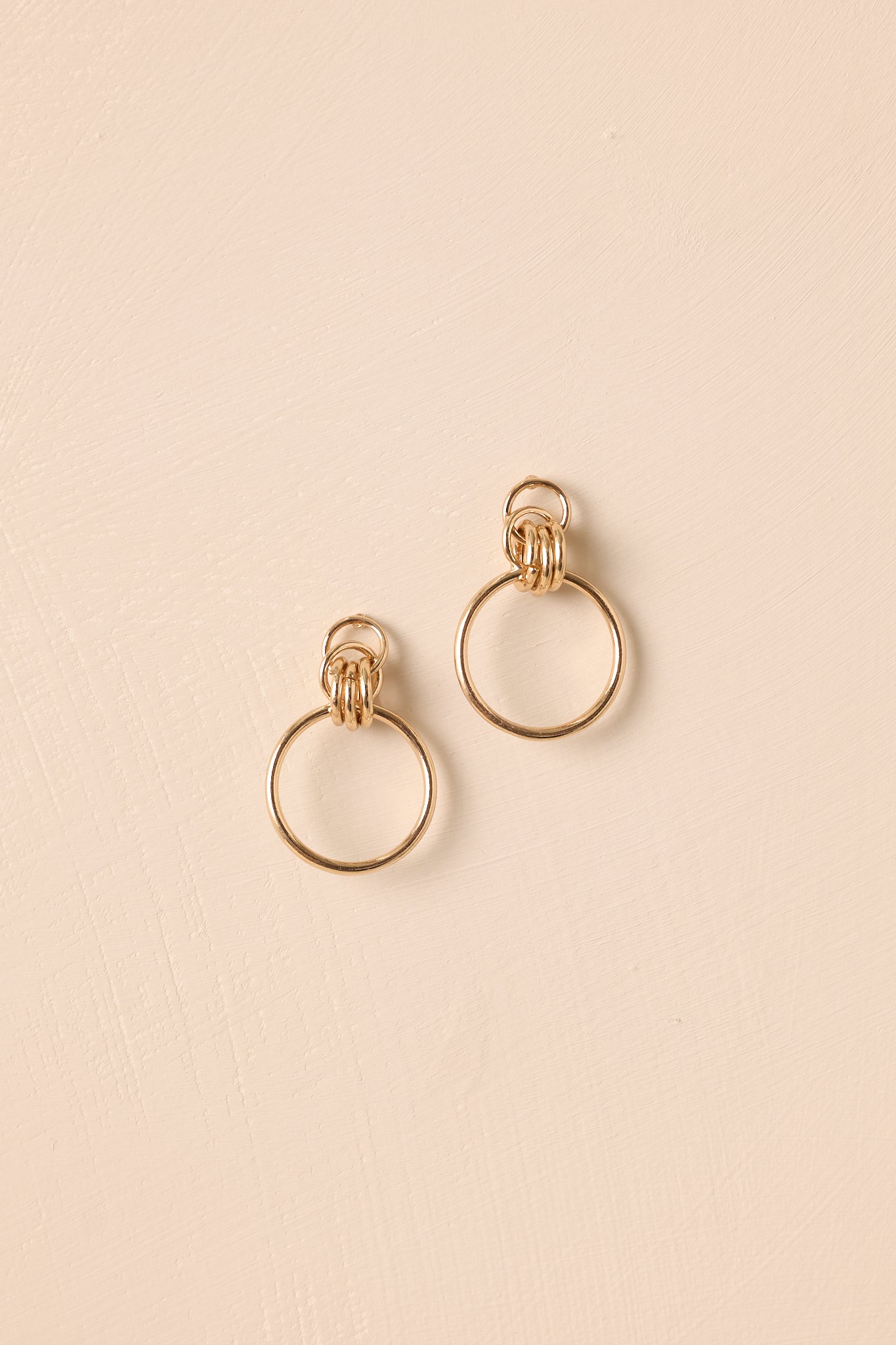 Pair of earrings displayed on a beige background, showing the interlocking link design.
