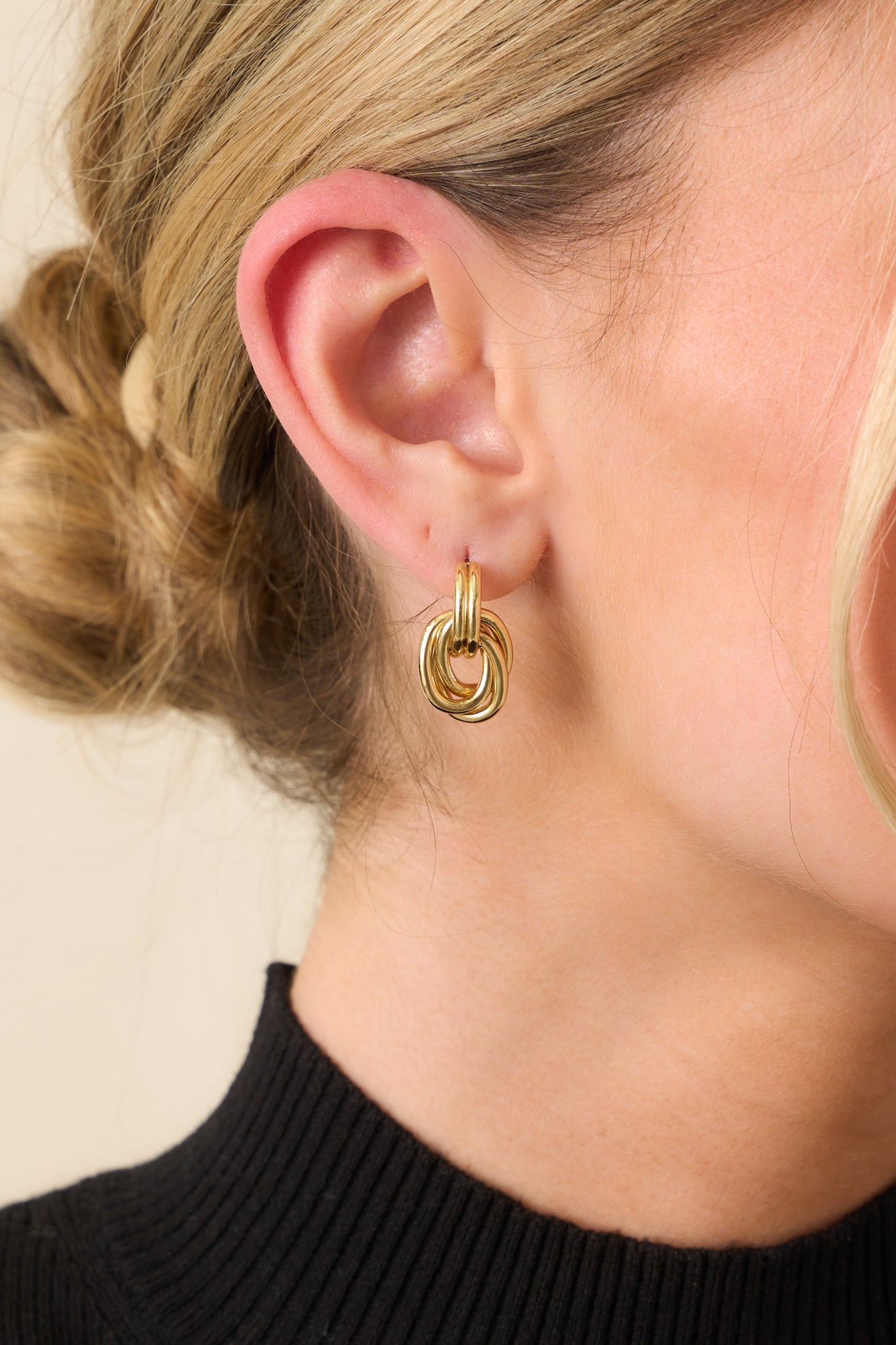 A close-up detail of the gold-colored interlocking hoops, showing the smooth layered curves and polished texture.