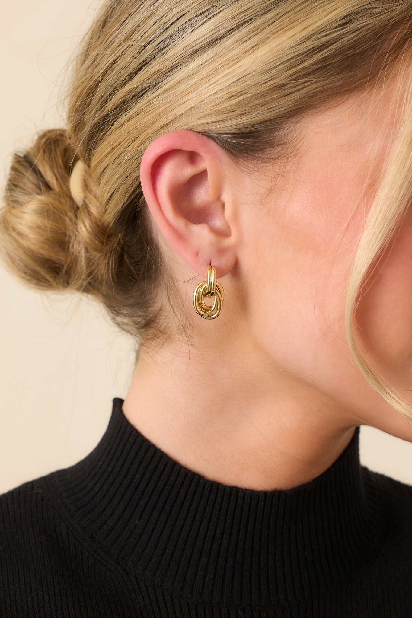 A cropped view of the earrings featuring a gold-colored finish and layered interlocking hoop design.