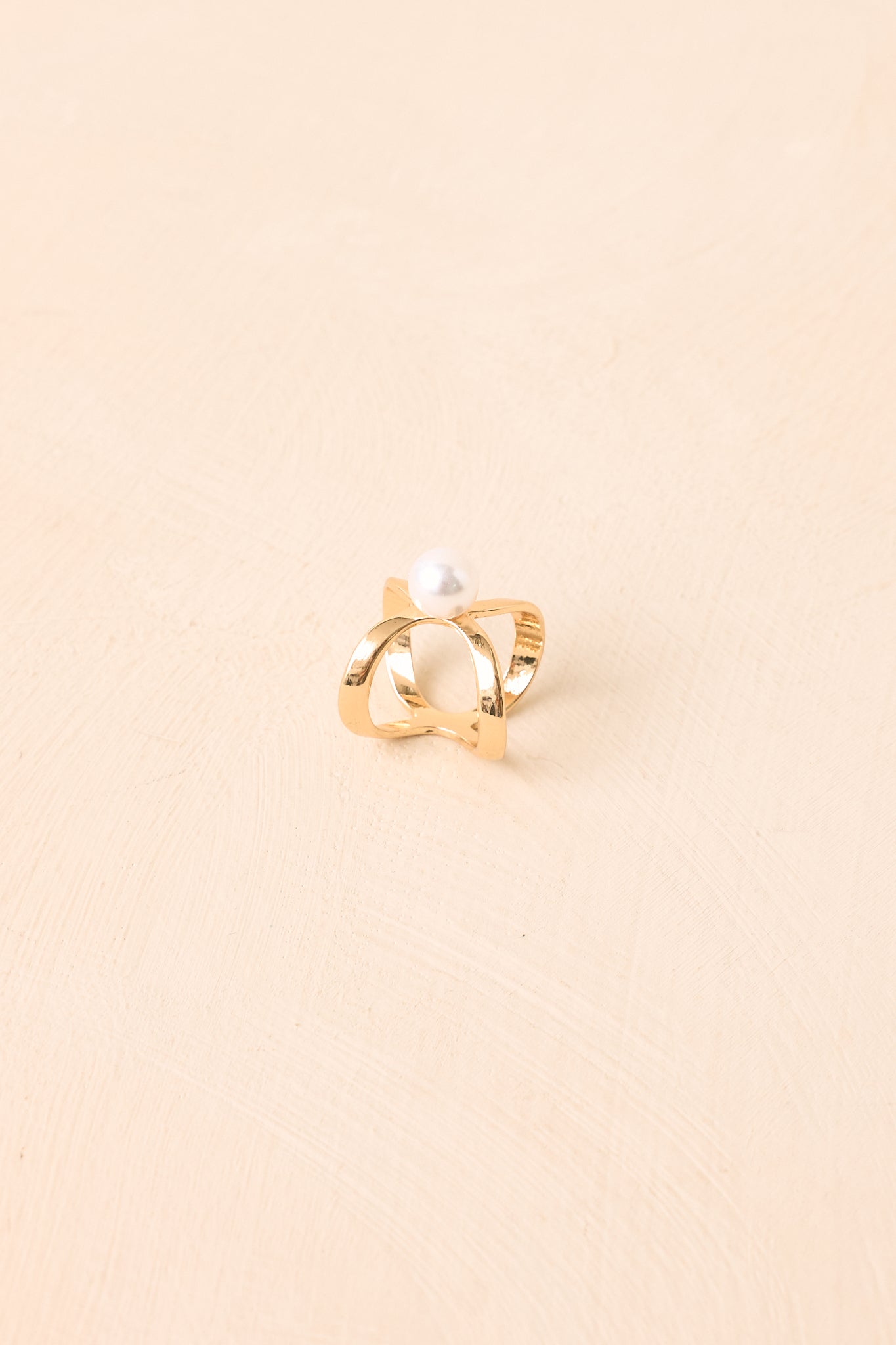 Polished gold scarf ring with an open geometric design and pearl detail.