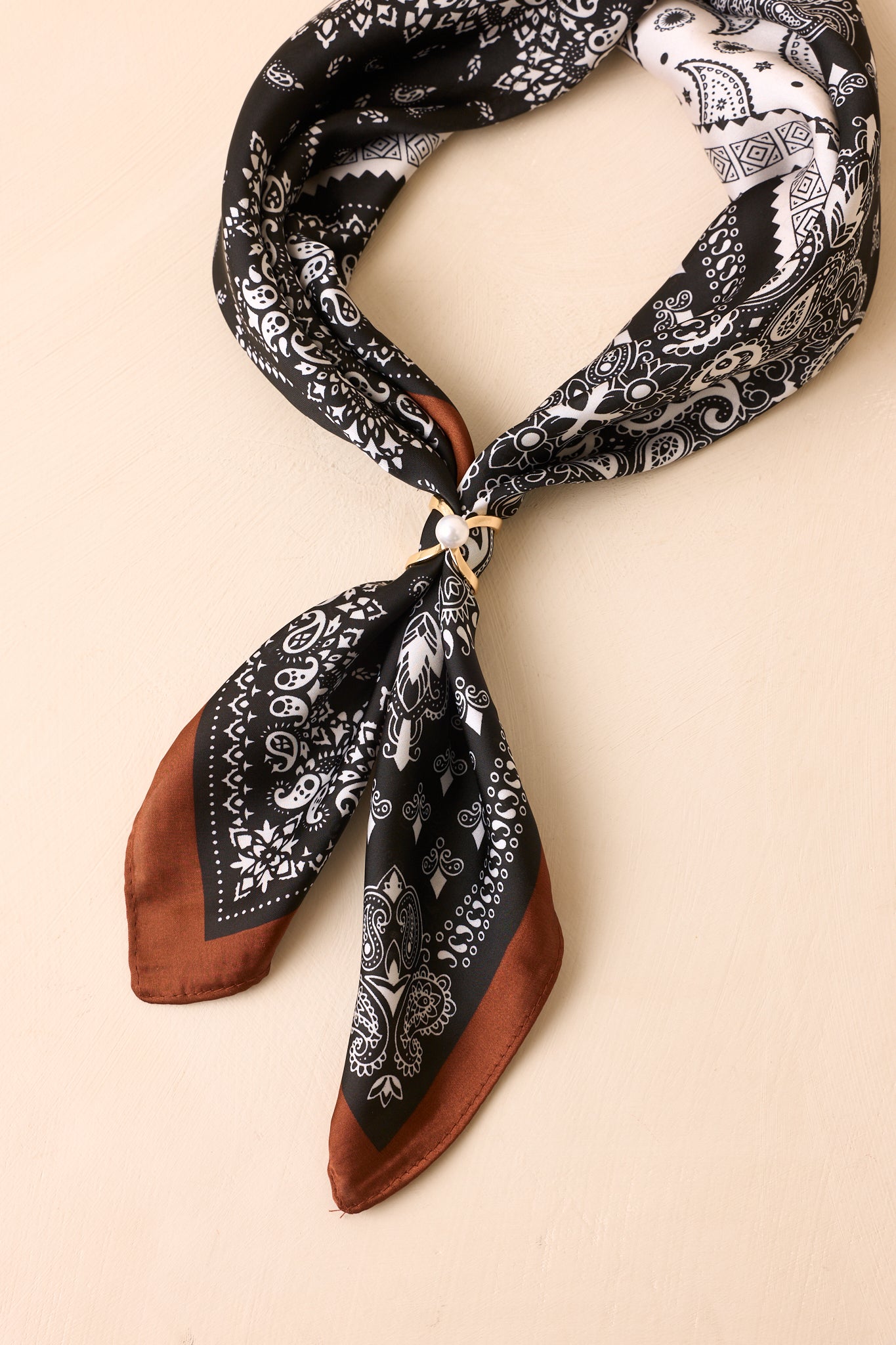 Gold scarf ring with a pearl accent styled with a black paisley bandana scarf.
