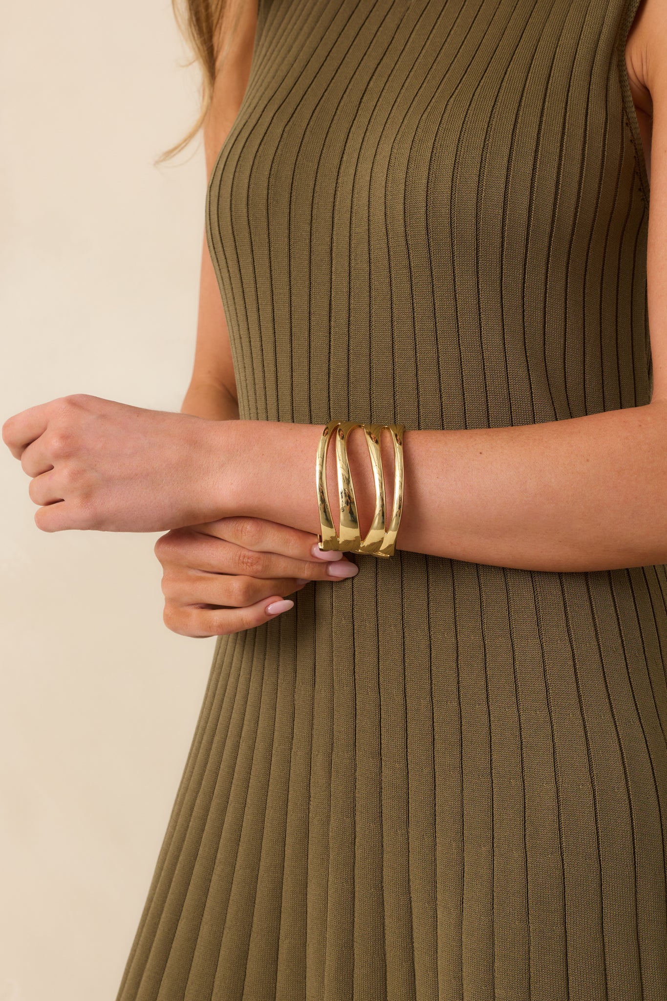 Gold cuff bracelet with three parallel wide flat bands, evenly spaced and connected by curved end caps, shown in a cropped view.