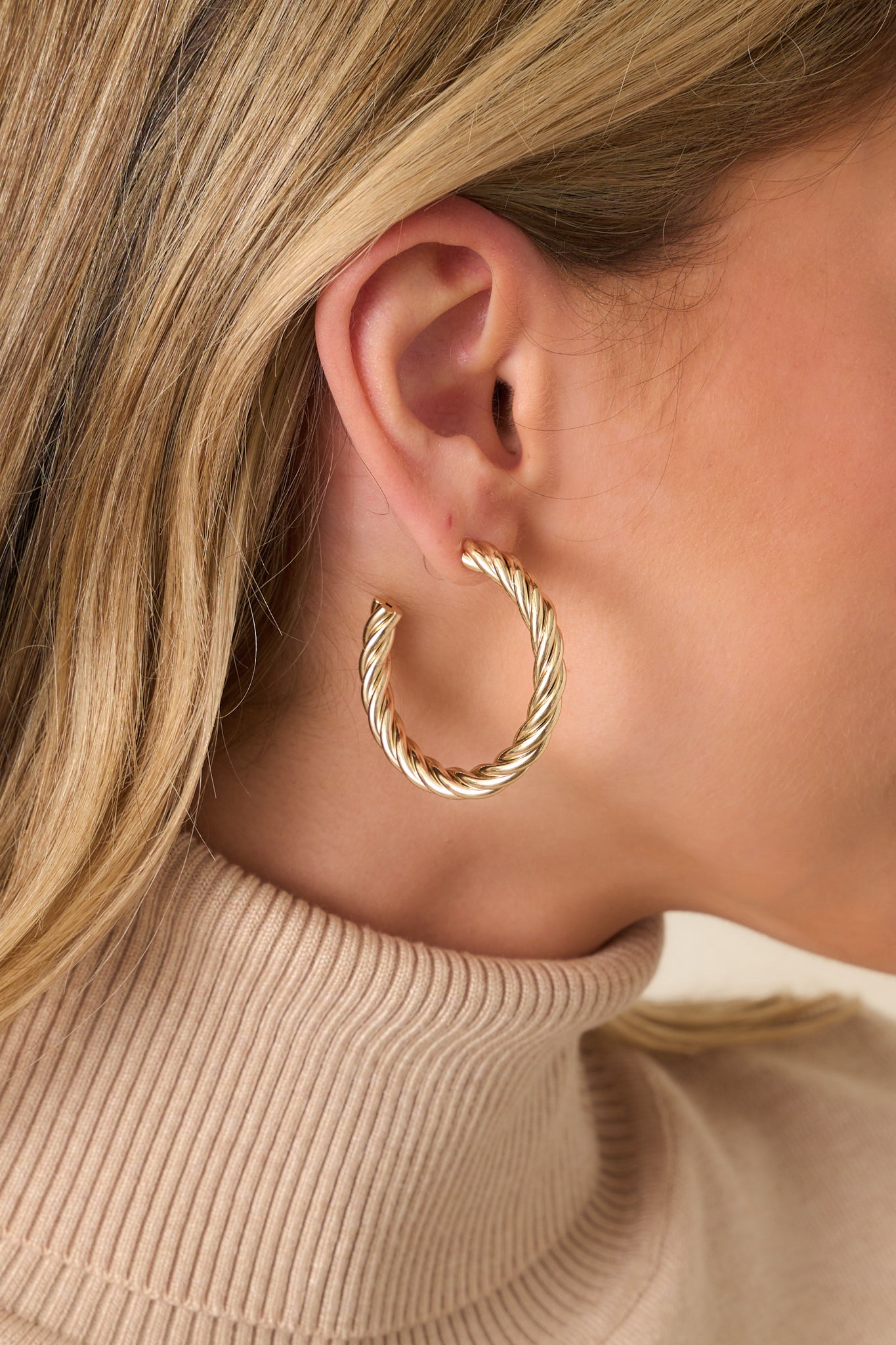 Cropped view of the gold-tone earrings showcasing the chunky twisted rope design and rounded hoop shape.