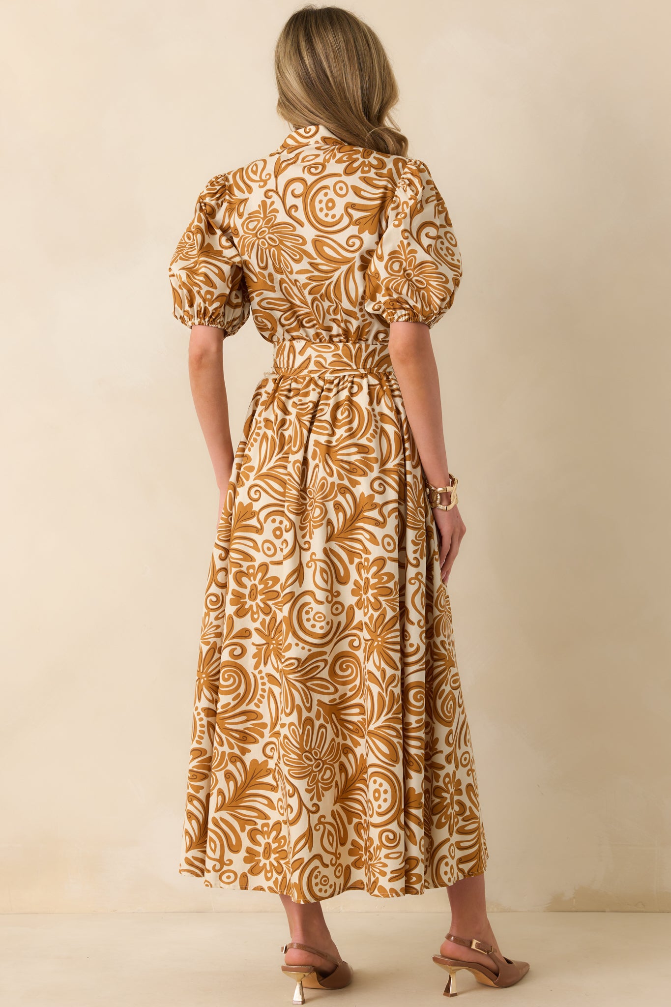 A view from behind of the golden yellow print maxi dress with short puff sleeves, elastic cuffs, and a full elastic waistband.