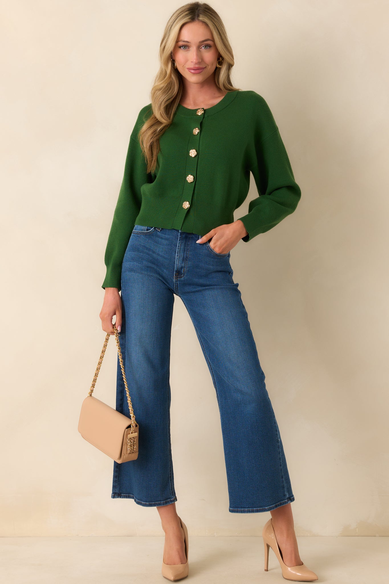 Front view of the hunter green cardigan worn buttoned up, featuring long sleeves and a crew neckline with a tapered fitted waistband.