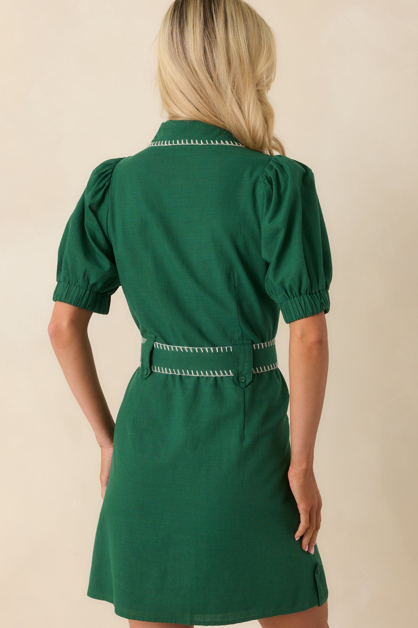 A back view of the dress highlighting the structured fit, puff sleeves, and continuation of white stitching along the seams.