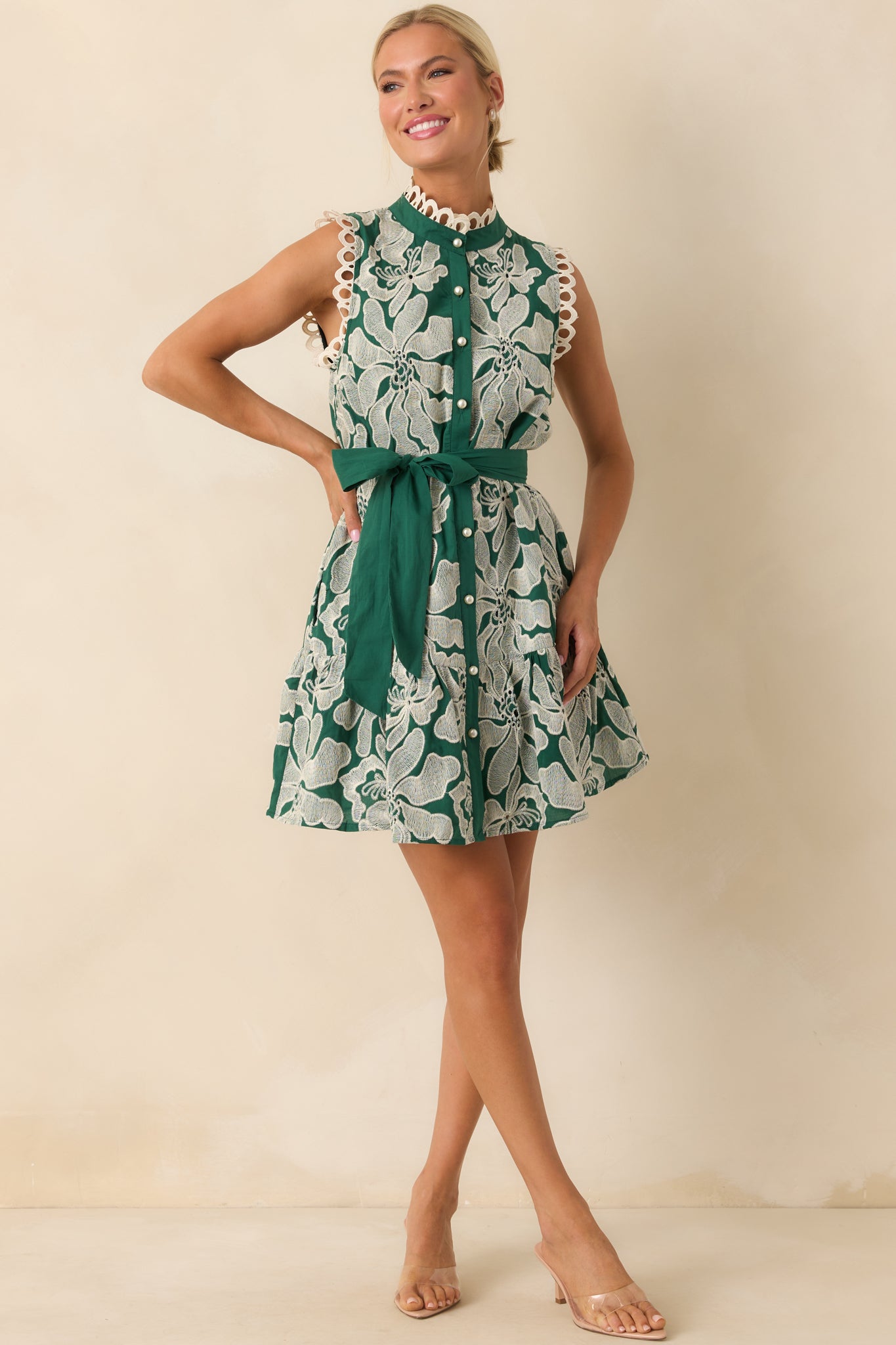 A full body front view of the emerald green mini dress with white floral embroidery and mock neckline.