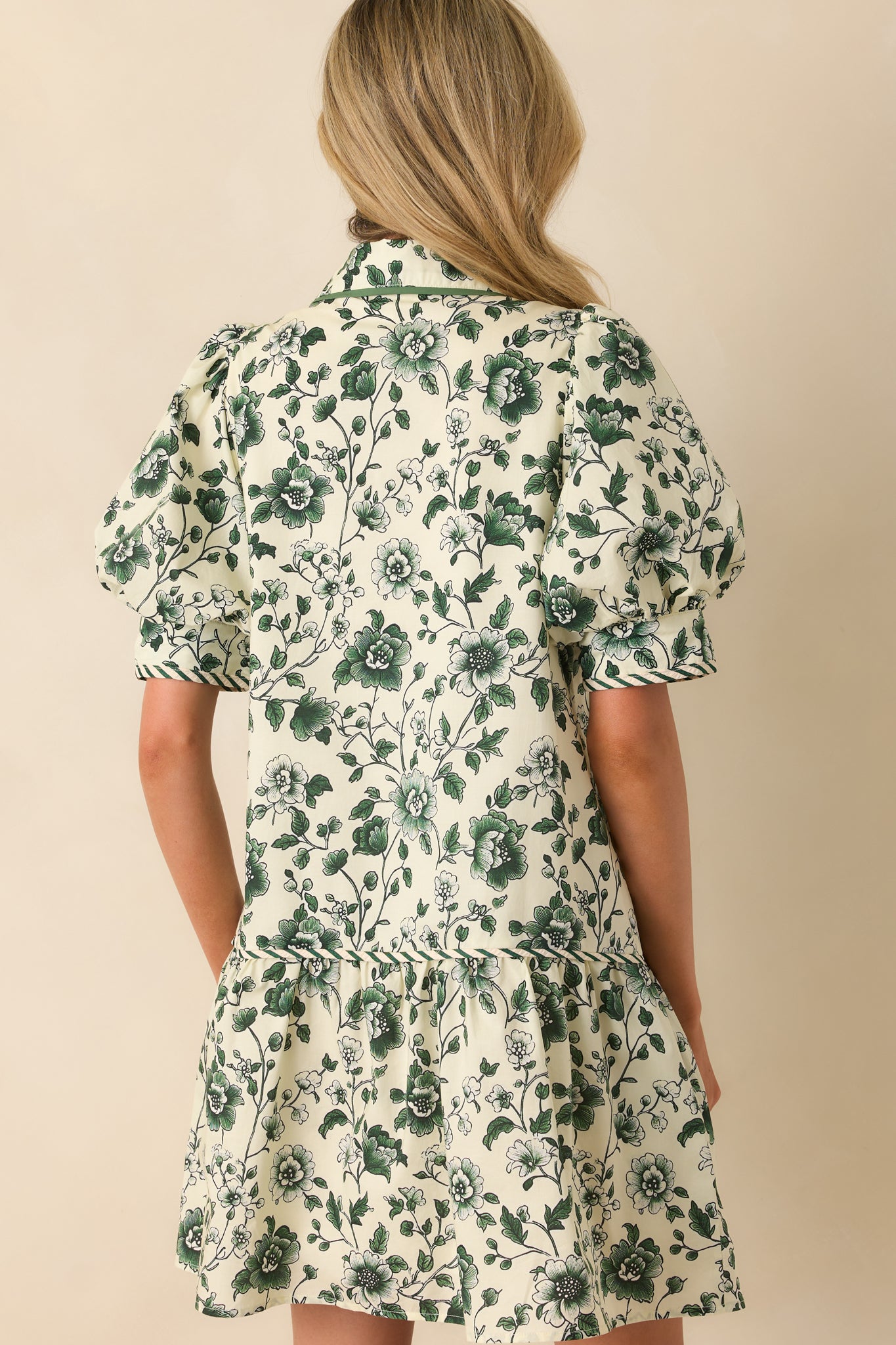 A back view of the mini dress showing the continuation of the green floral print and full ivory lining.