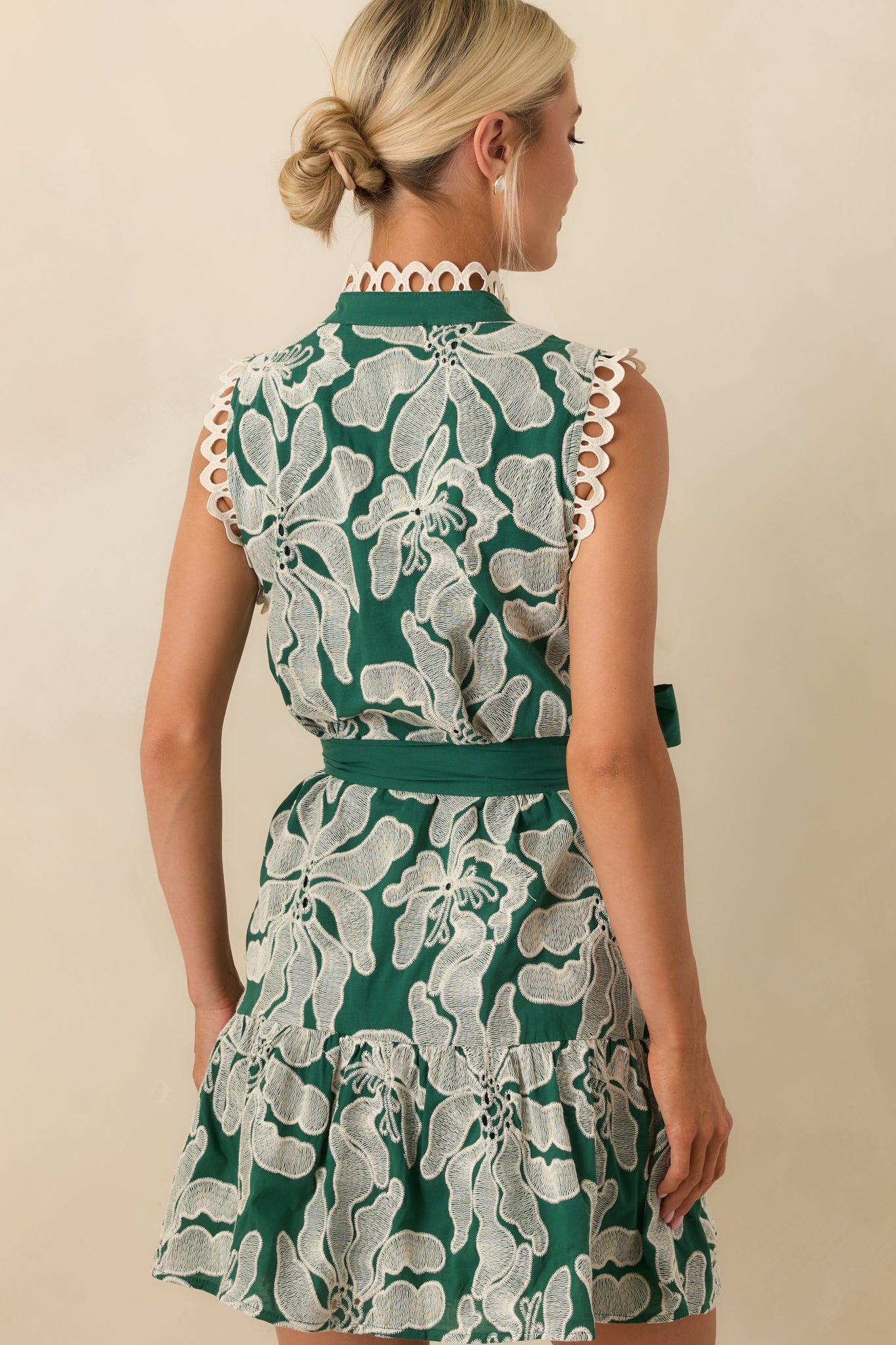 A back view of the mini dress displaying the full green lining and rear fit of the embroidered design.