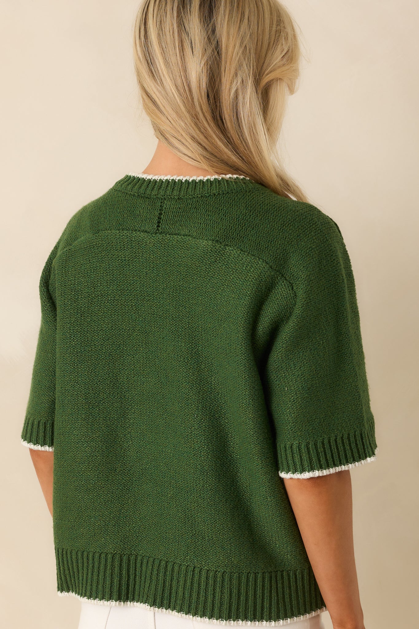 A view from behind of green oversized sweater with ivory contrast trim and ribbed hems.