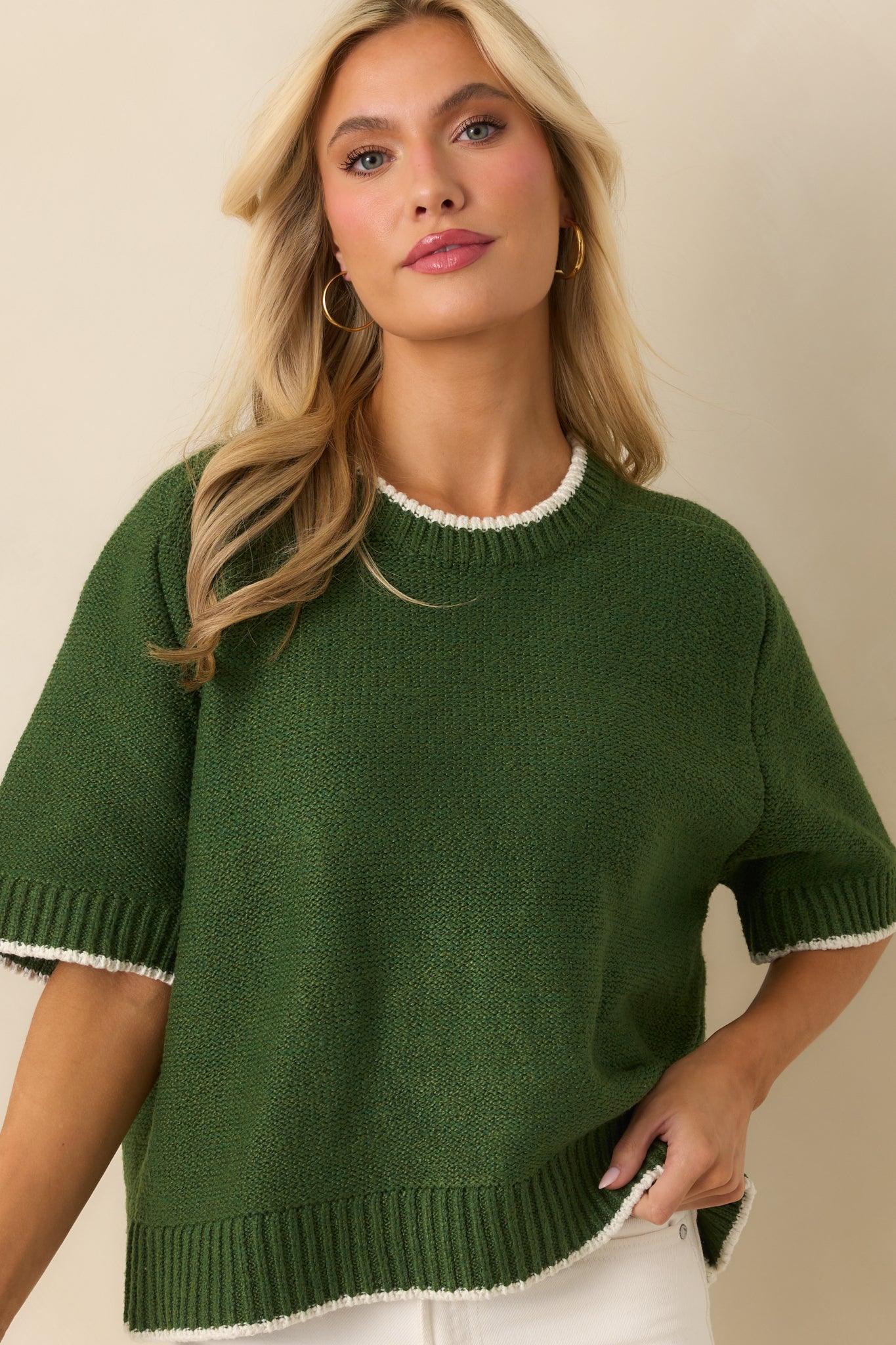 Close view of green knit sweater with oversized fit and short sleeve detail
