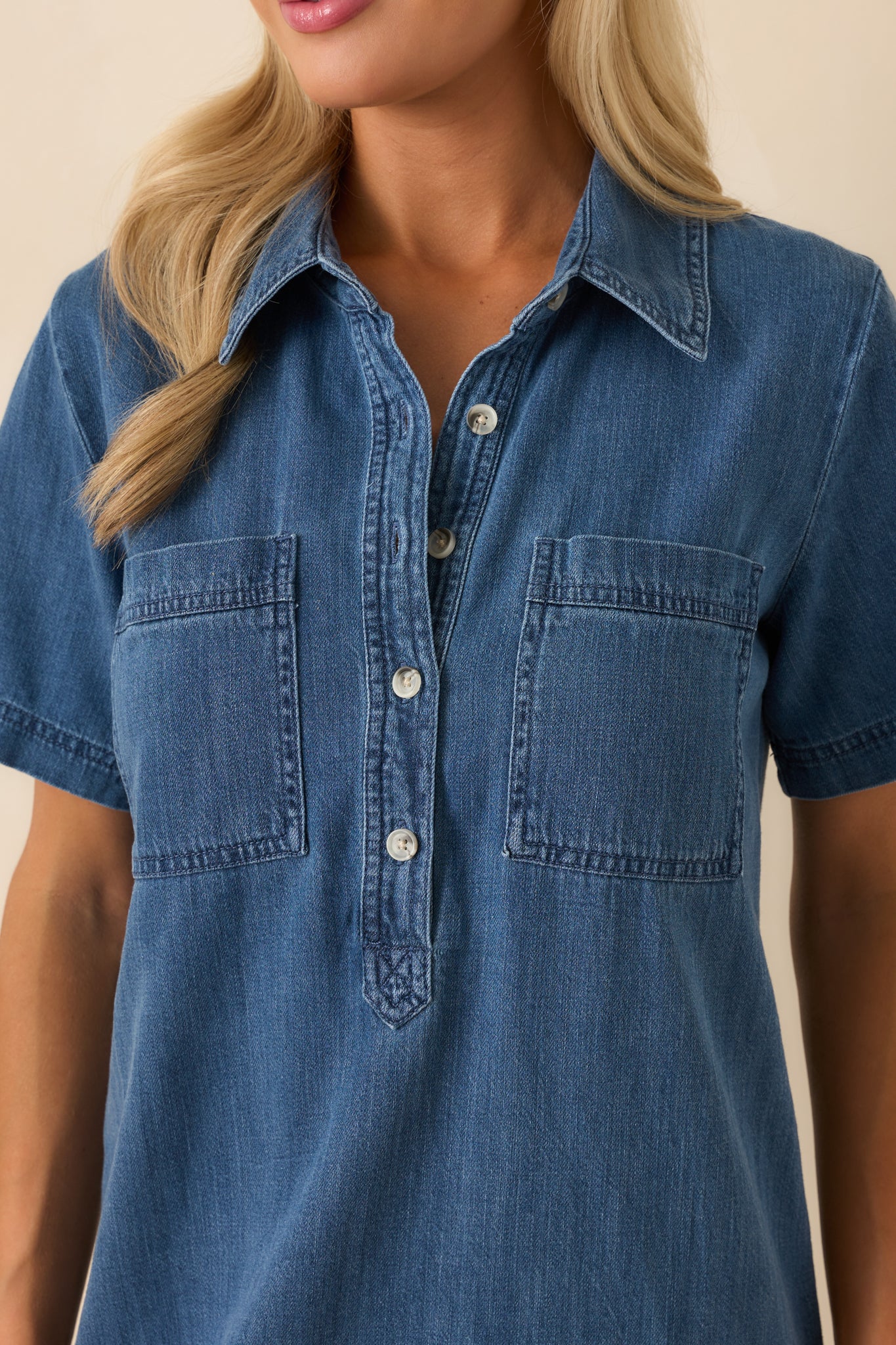 Close-up of the cotton fabric and button placket, capturing the texture of the medium wash material and fine stitching detail.