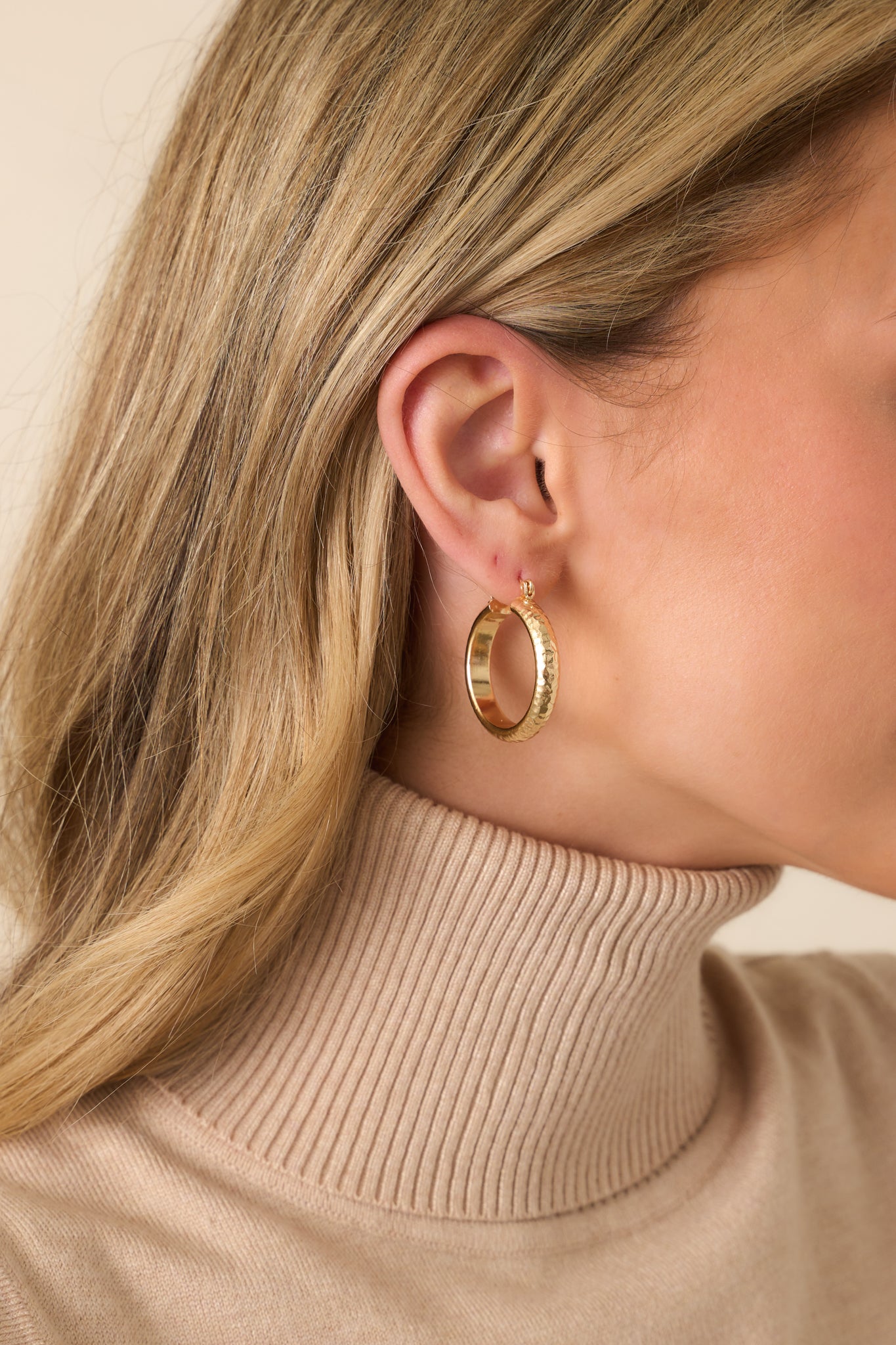 A close-up detail of the earring’s hammered texture and latch back post closure, highlighting the intricate surface finish.