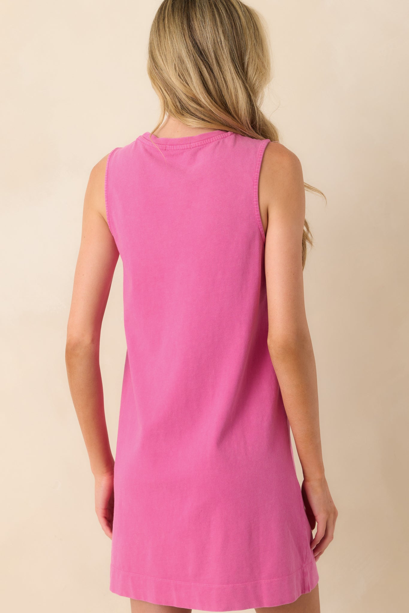 A view from behind of the pink mini dress showing the sleeveless design, relaxed fit, and straight hemline.
