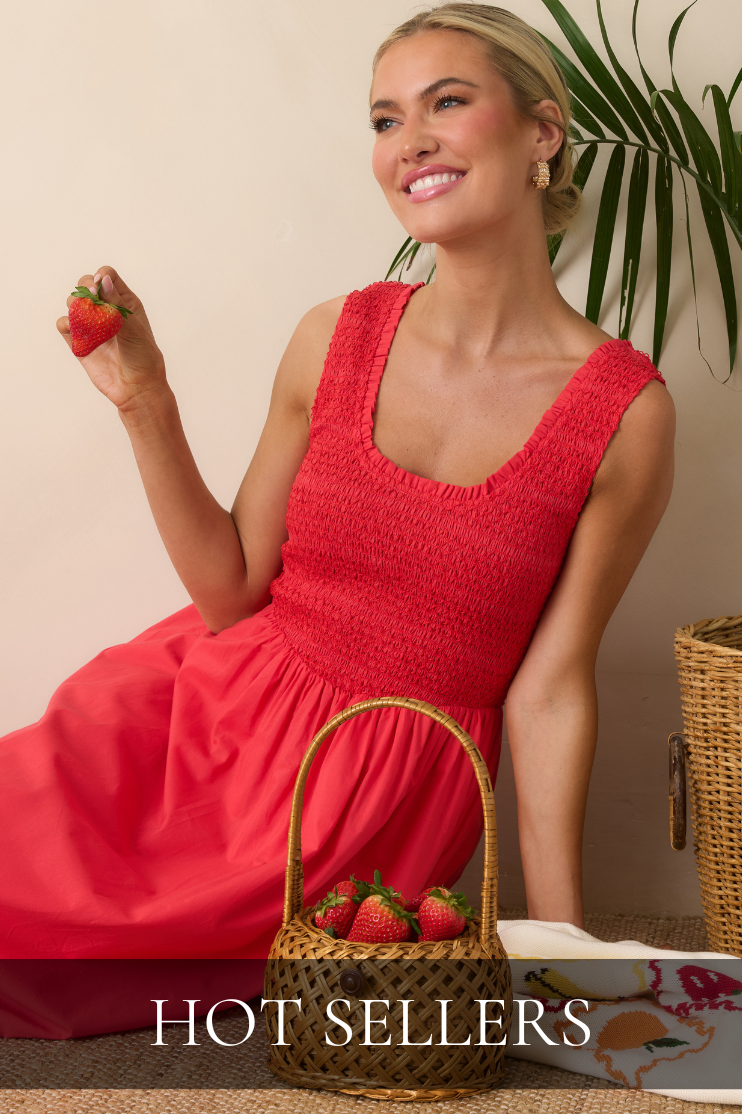 Model wearing a bright red smocked midi dress holding a strawberry featured in the Red Dress Hot Sellers collection.