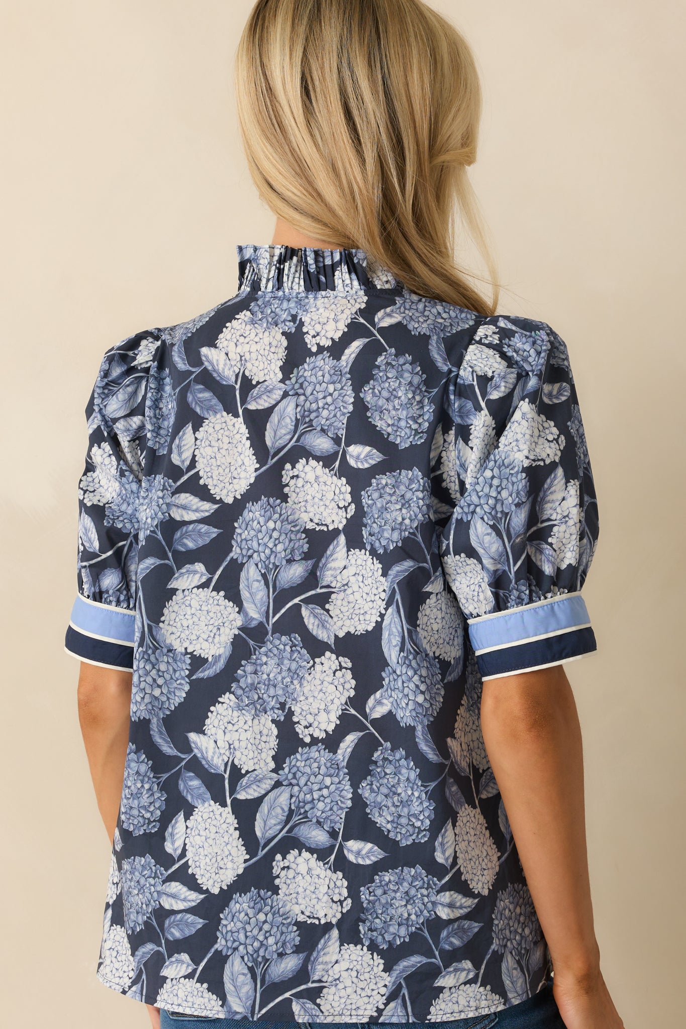 Rear view of the hydrangea print blouse with relaxed fit and cuffed sleeves.