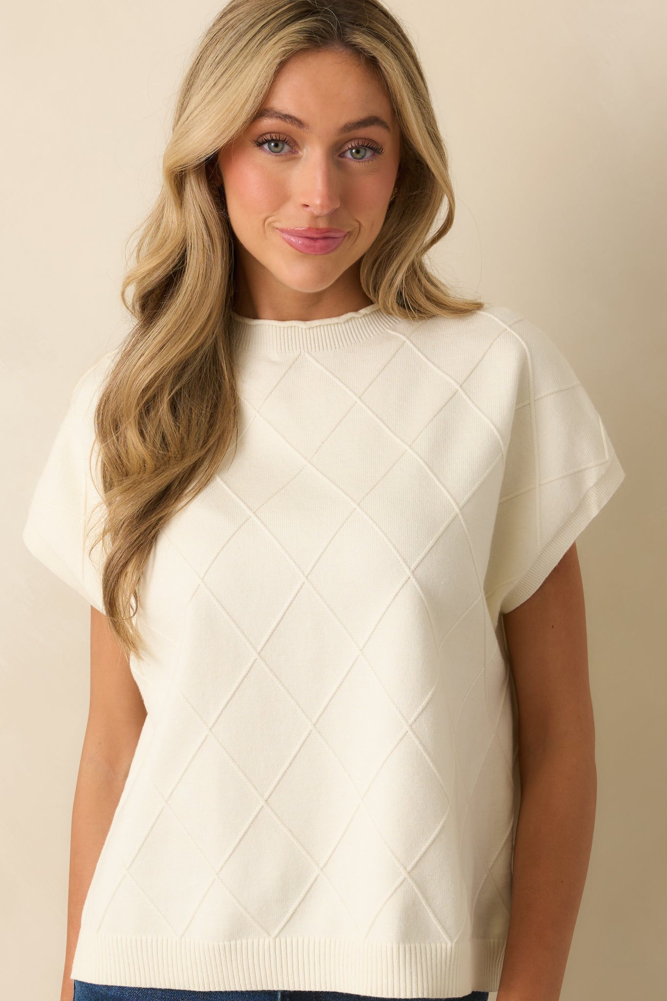 Close view of the argyle stitch pattern on the front of the ivory sweater.
