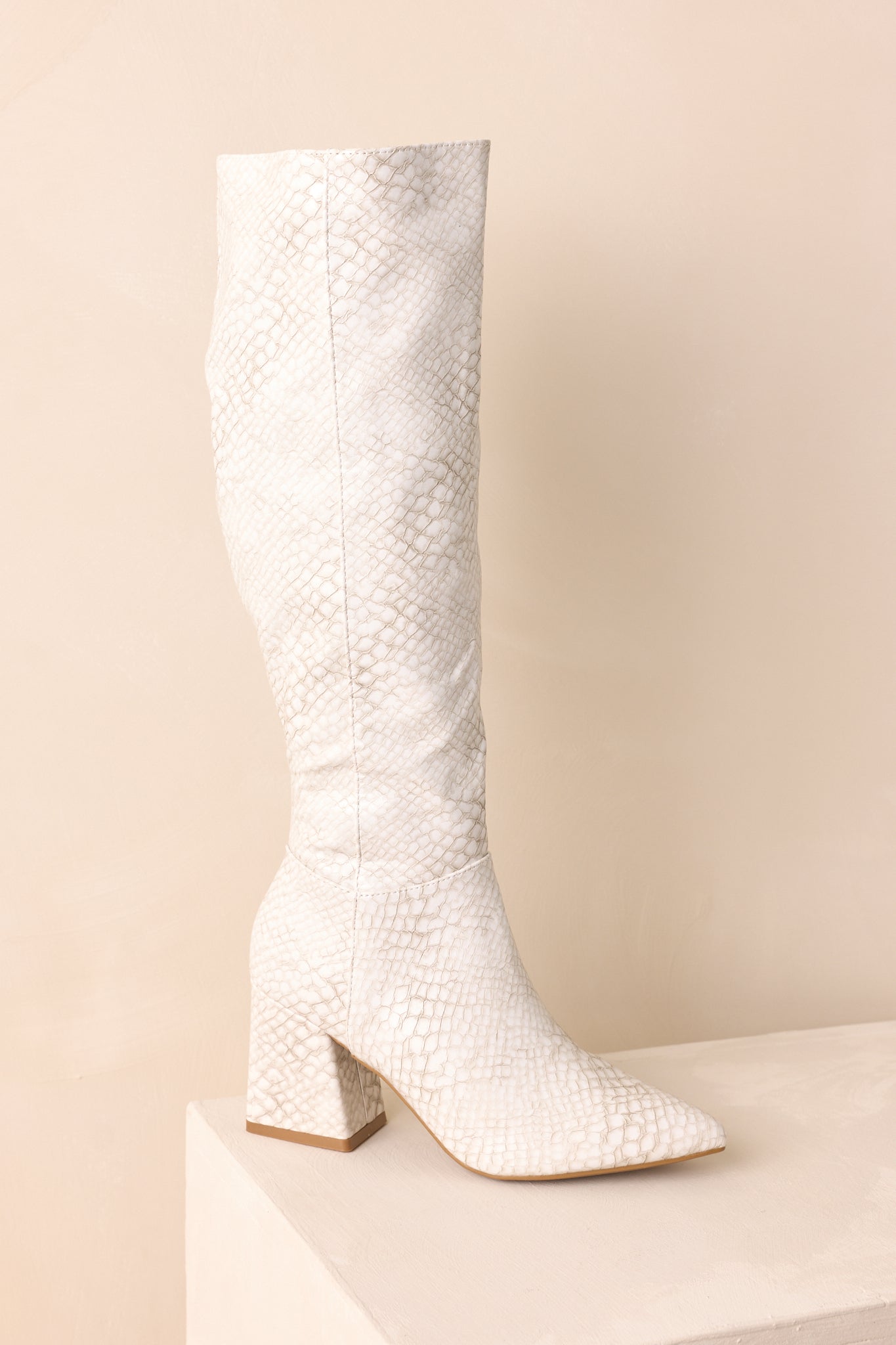 Another side shot of the ivory boots emphasizing the structured panel lines and snakeskin finish.