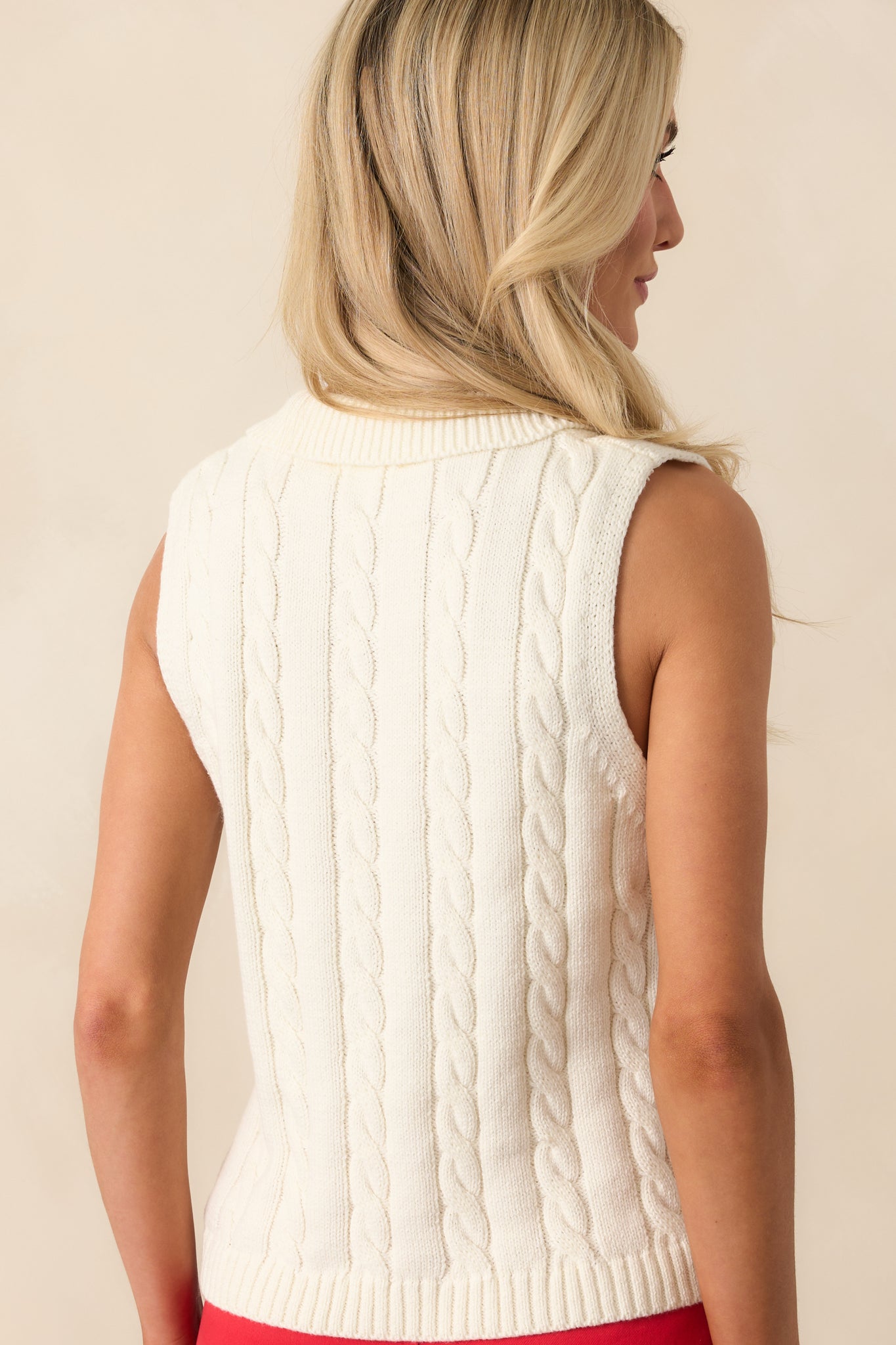 A back view of the sweater vest showing the continuous cable knit pattern and ribbed hem for a structured finish.