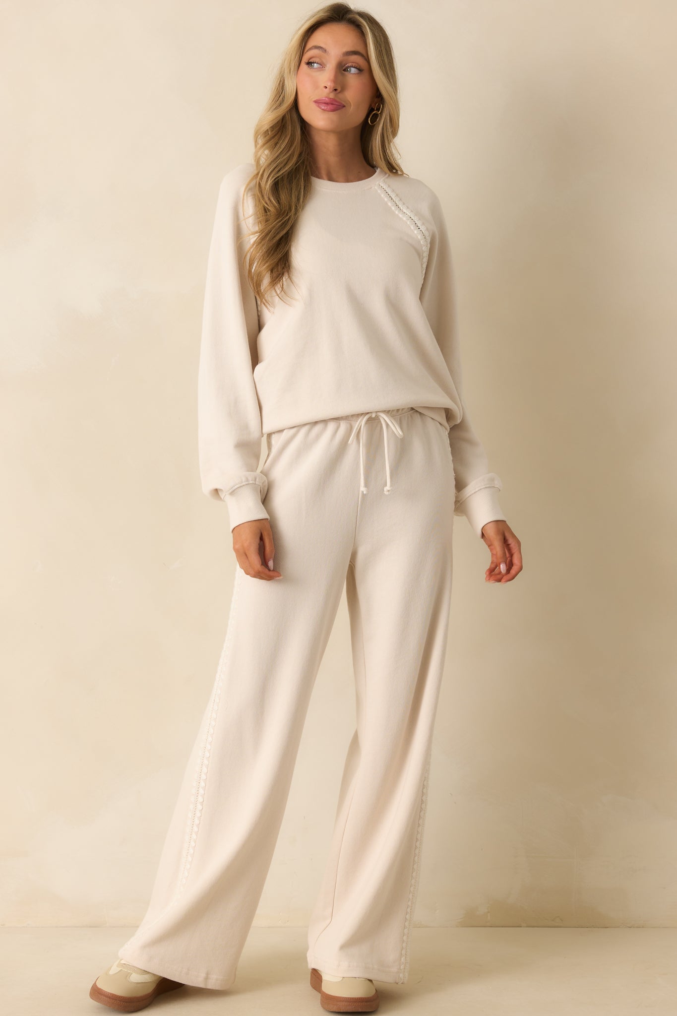 Ivory pants highlighting the crochet side trim and soft wide leg design.