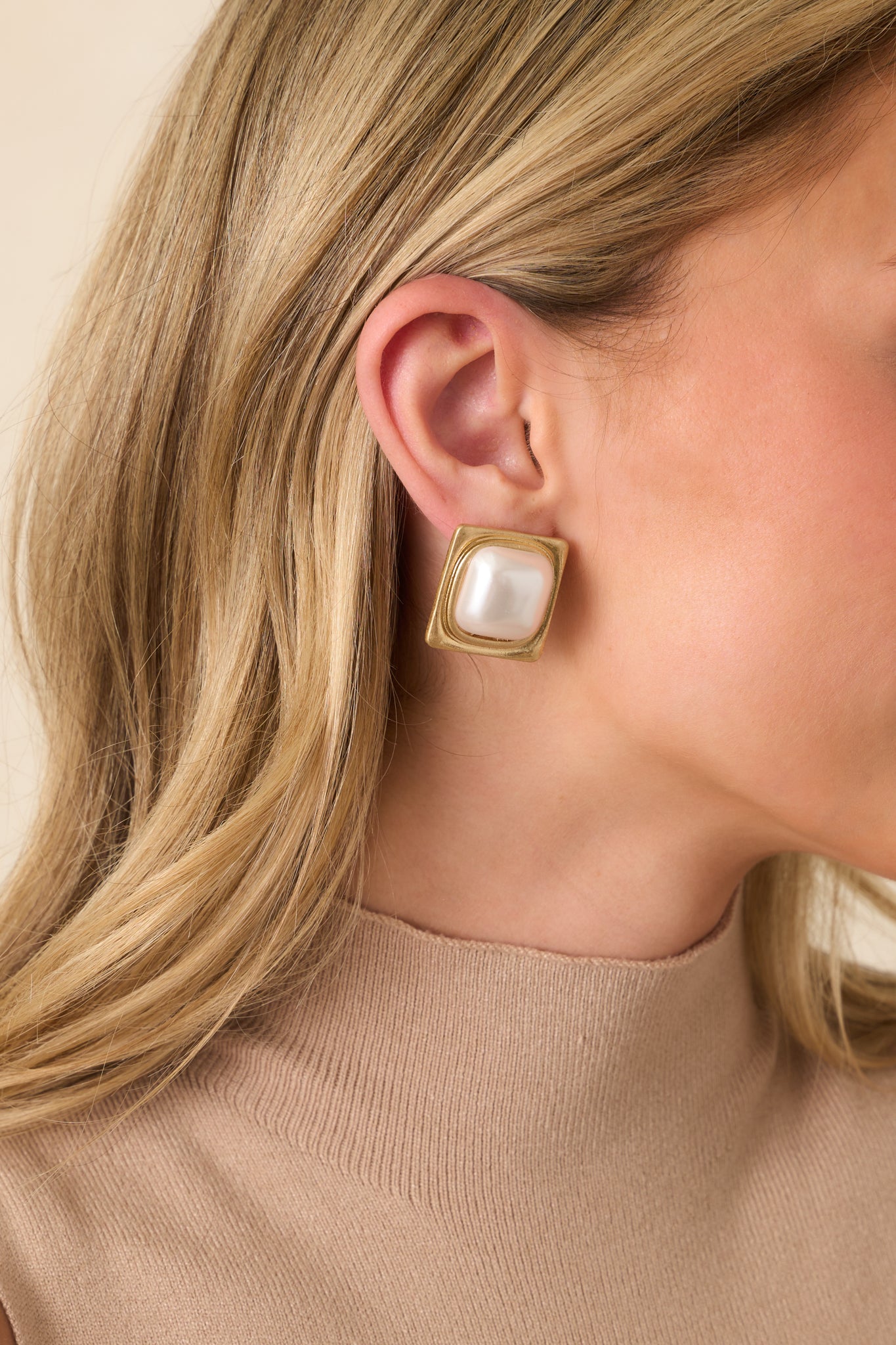 Cropped view of the earrings highlighting the ivory faux pearl center and the textured square gold-tone frame.