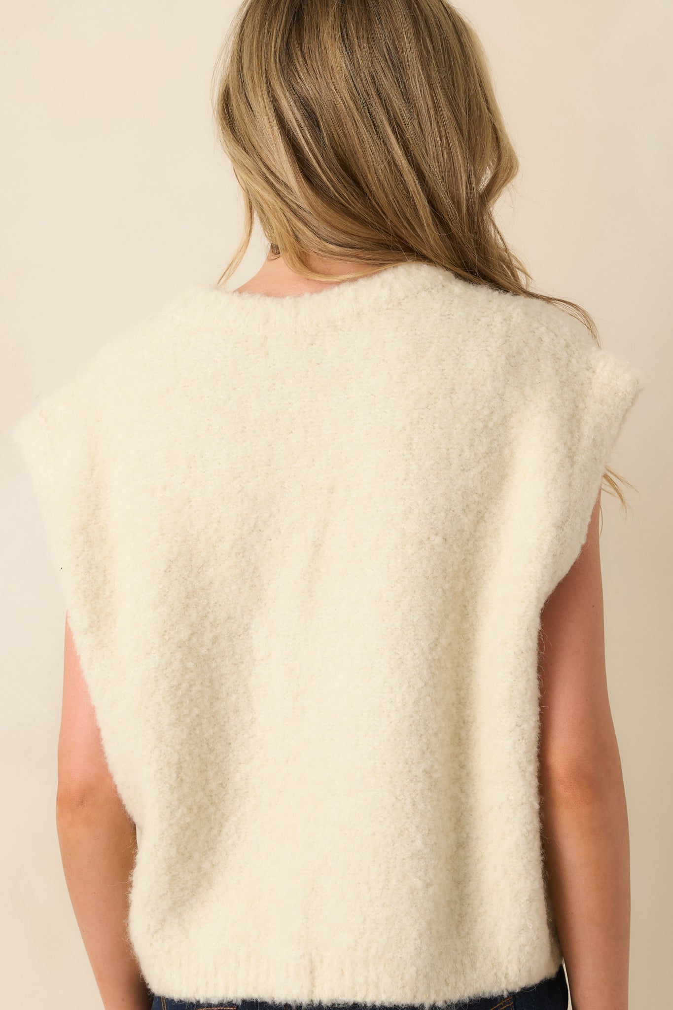 Rear view of the ivory sweater vest showing the smooth knit fabric and sleeveless cut.
